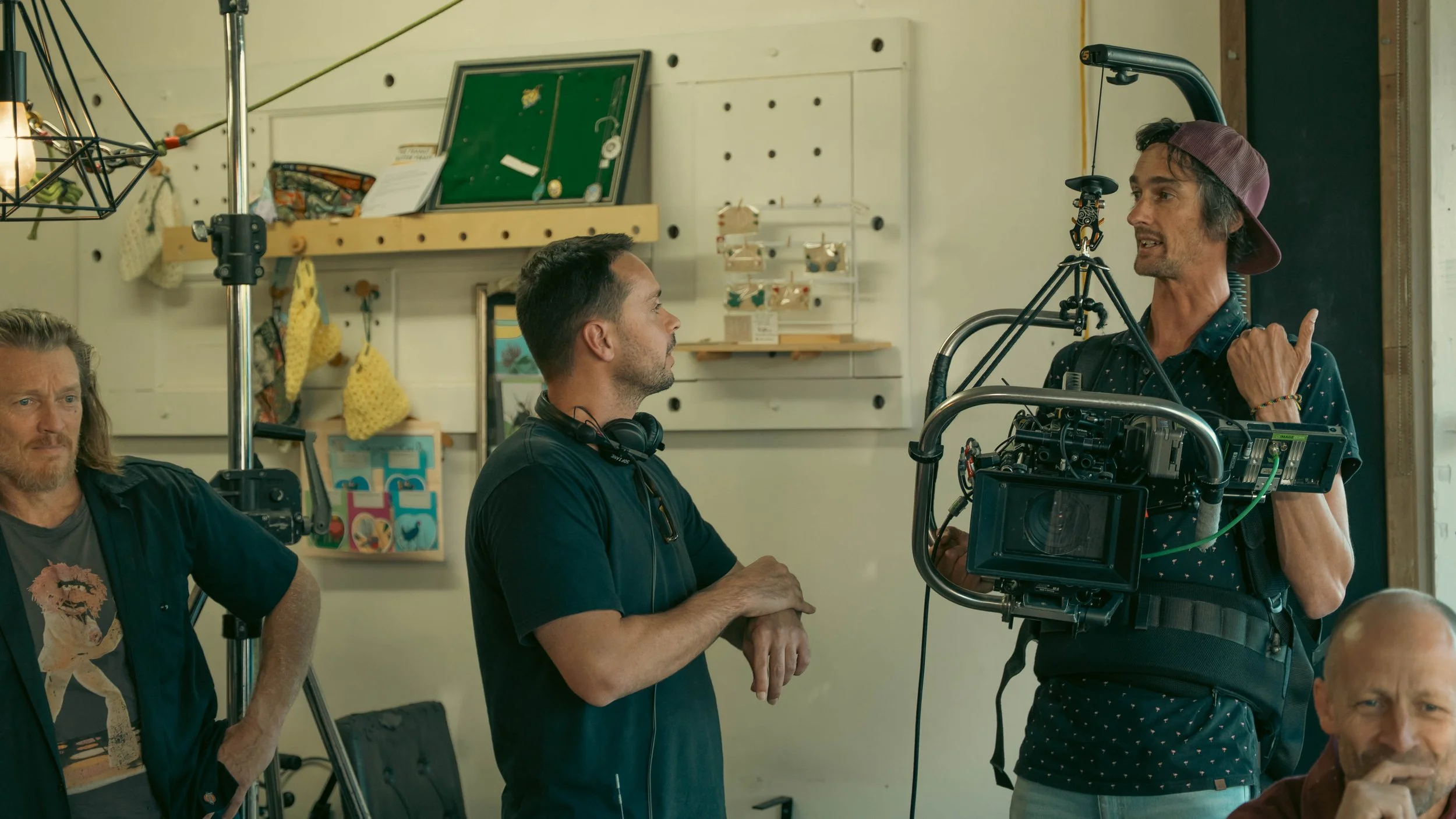 Filmmakers on set with camera and crew members in a room with shelves and decorations.