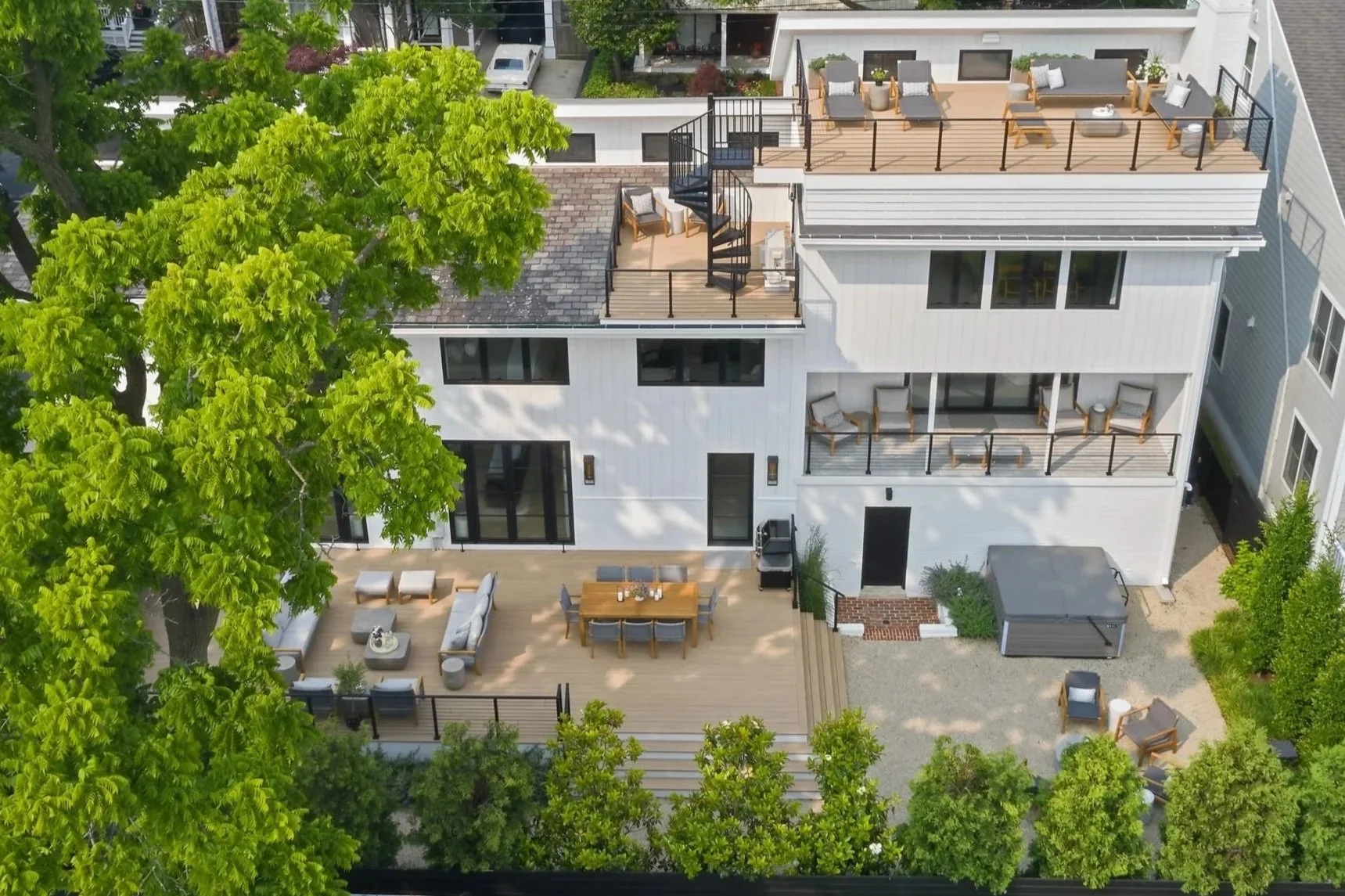 Modern Annapolis home exterior featuring layered outdoor living spaces with rooftop deck, outdoor dining, and integrated landscape design