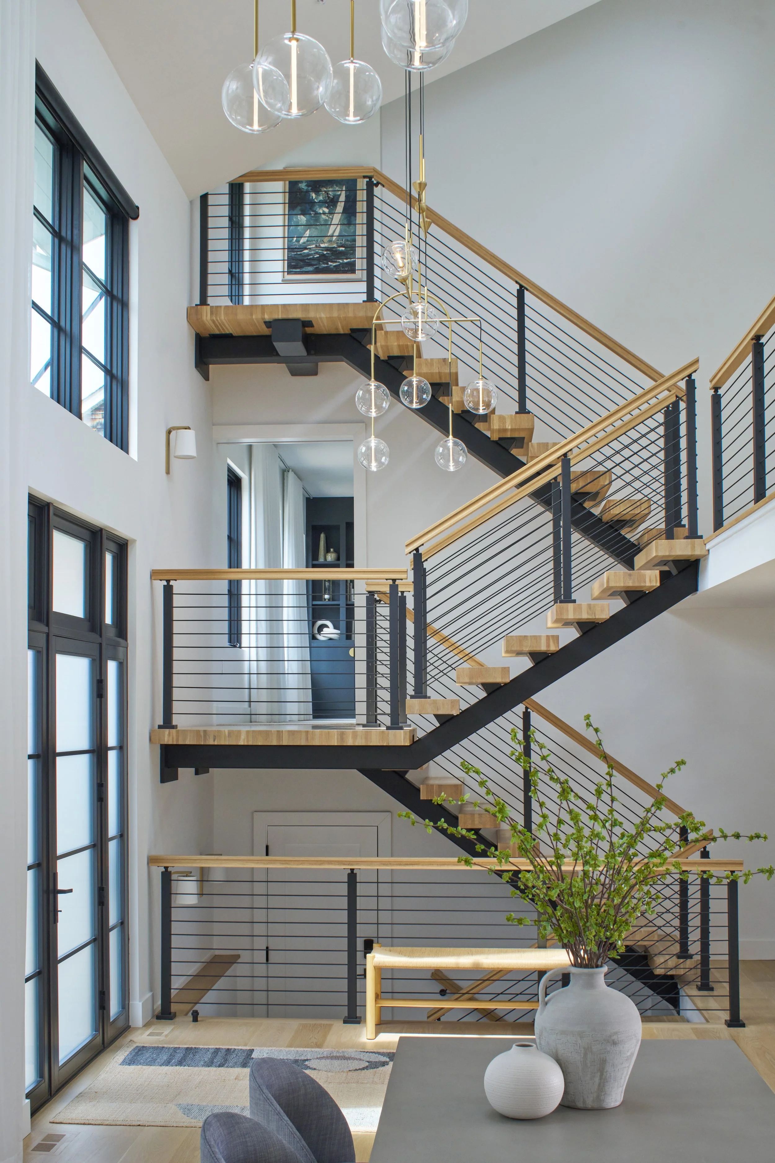 Modern Annapolis foyer and dining area with sculptural globe chandelier and floating wood staircase