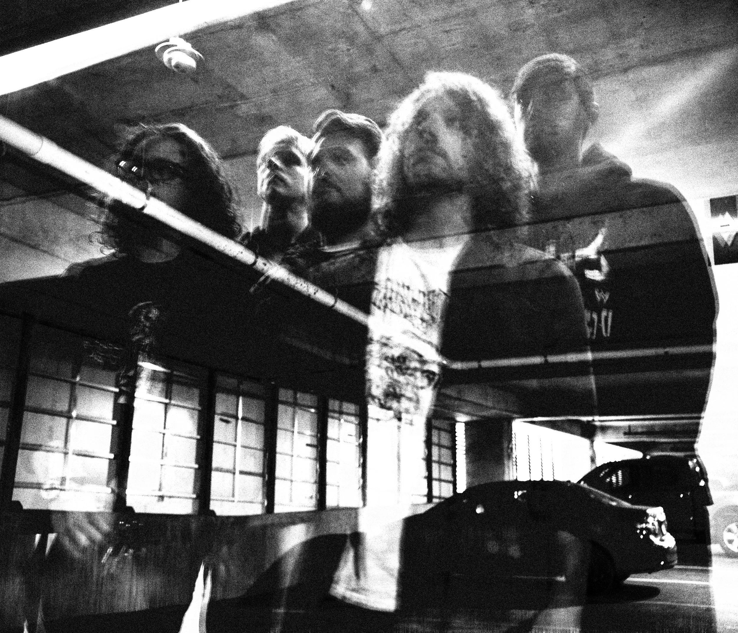 reflection of five band members photographed in black and white in a parking garage.