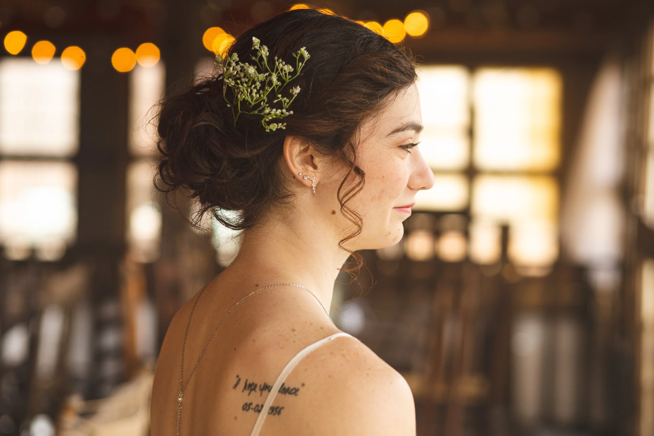 Side profile of bride at barndominum wedding venue. Golden hour light falling through windows. 