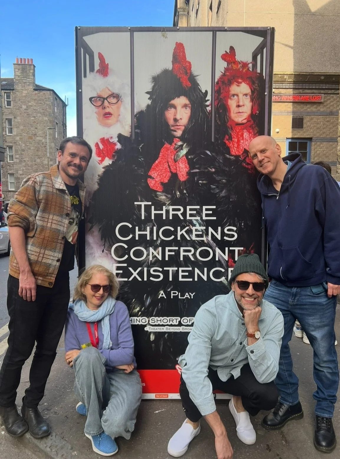 Bill Schaumberg, Audrey Rapoport, Matthew DiLoreto, and Eric Kirchberger in Edinburgh, Scotland alongside a poster for Three Chickens Confront Existence