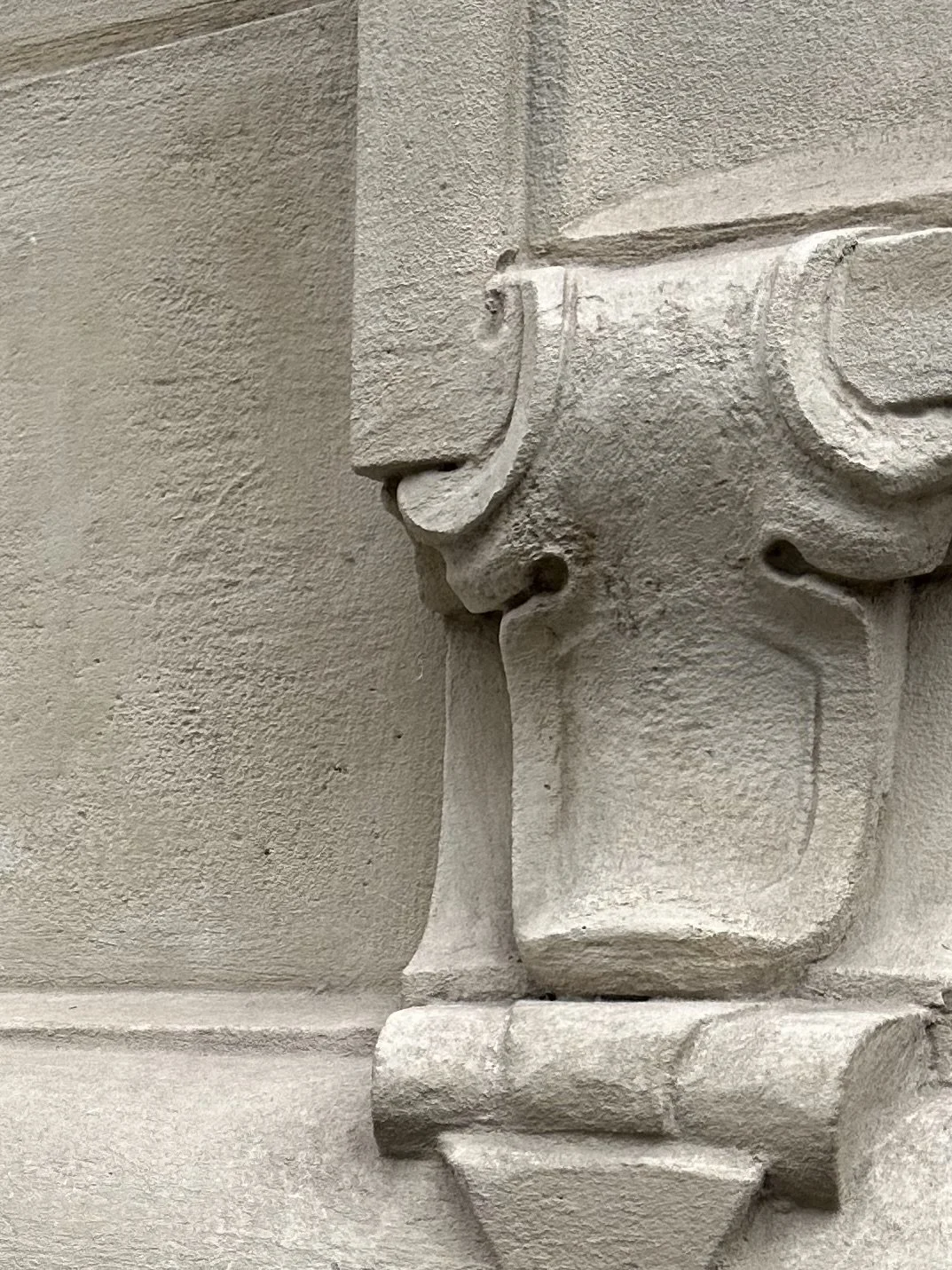 Détail d'une sculpture en pierre représentant une figure humaine, probablement un visage avec un nez et une lèvre.