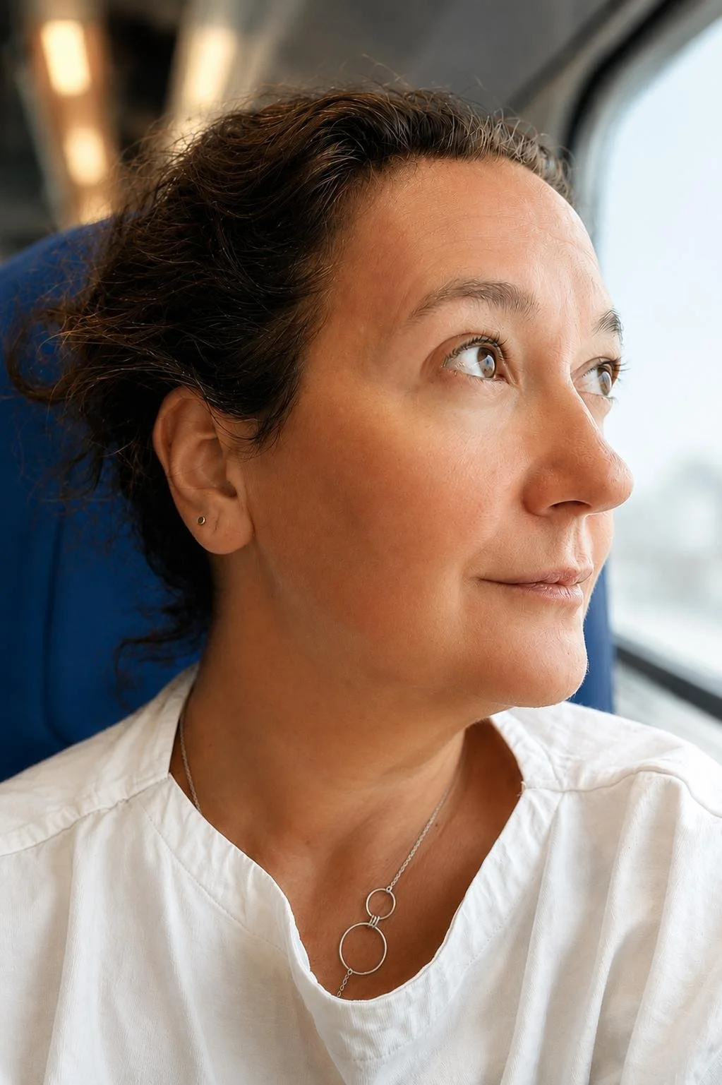 Maternity nurse and life coach for women Solange Martins is looking out the window in a train or bus.