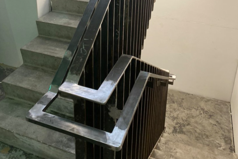 View of a concrete staircase with metal handrails, seen from the top of the staircase looking downward.
