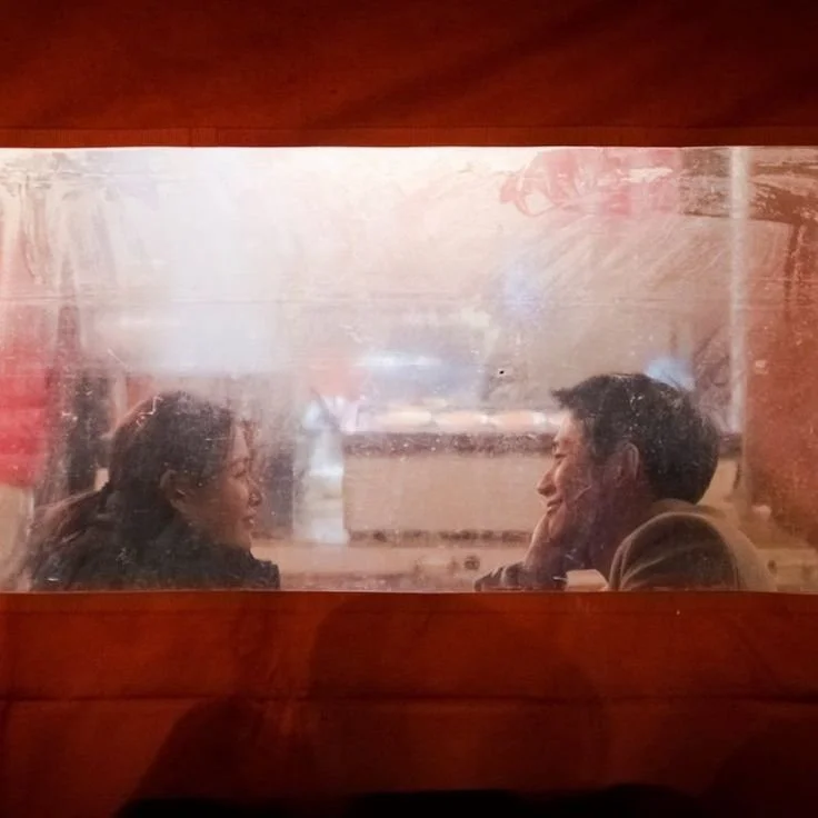 A romantic couple seen through a restaurant window, engaging in conversation.