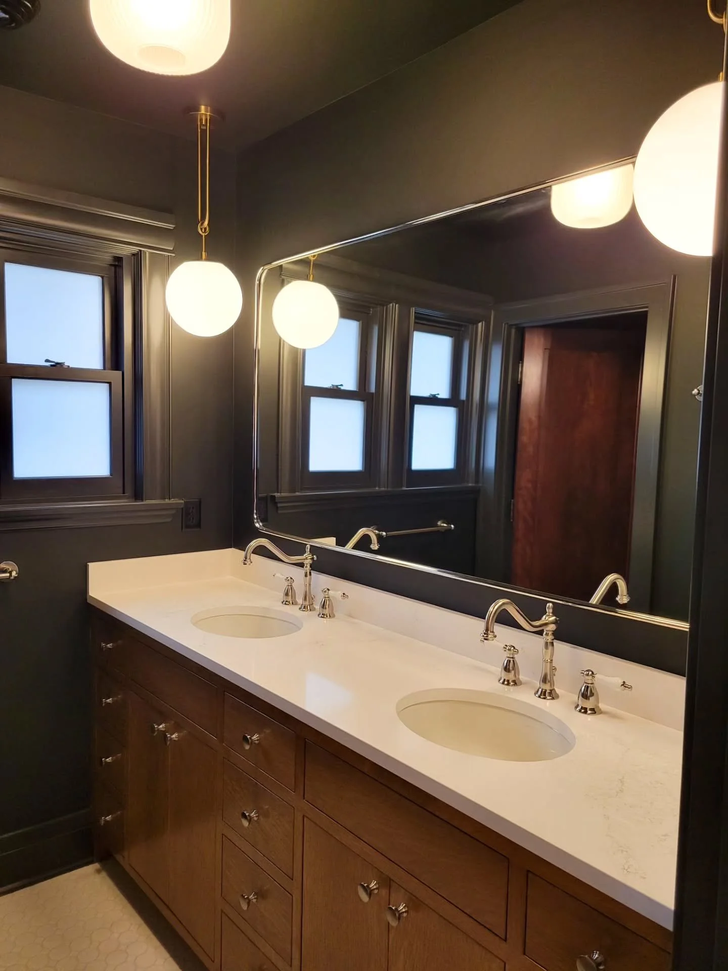 This hallway bath got a major upgrade ✨️ we expanded the layout to give each area its own space, making it much more functional for this family’s kids. The deep green walls add a moody contrast to the bright white tile and warm wood tones. Desi