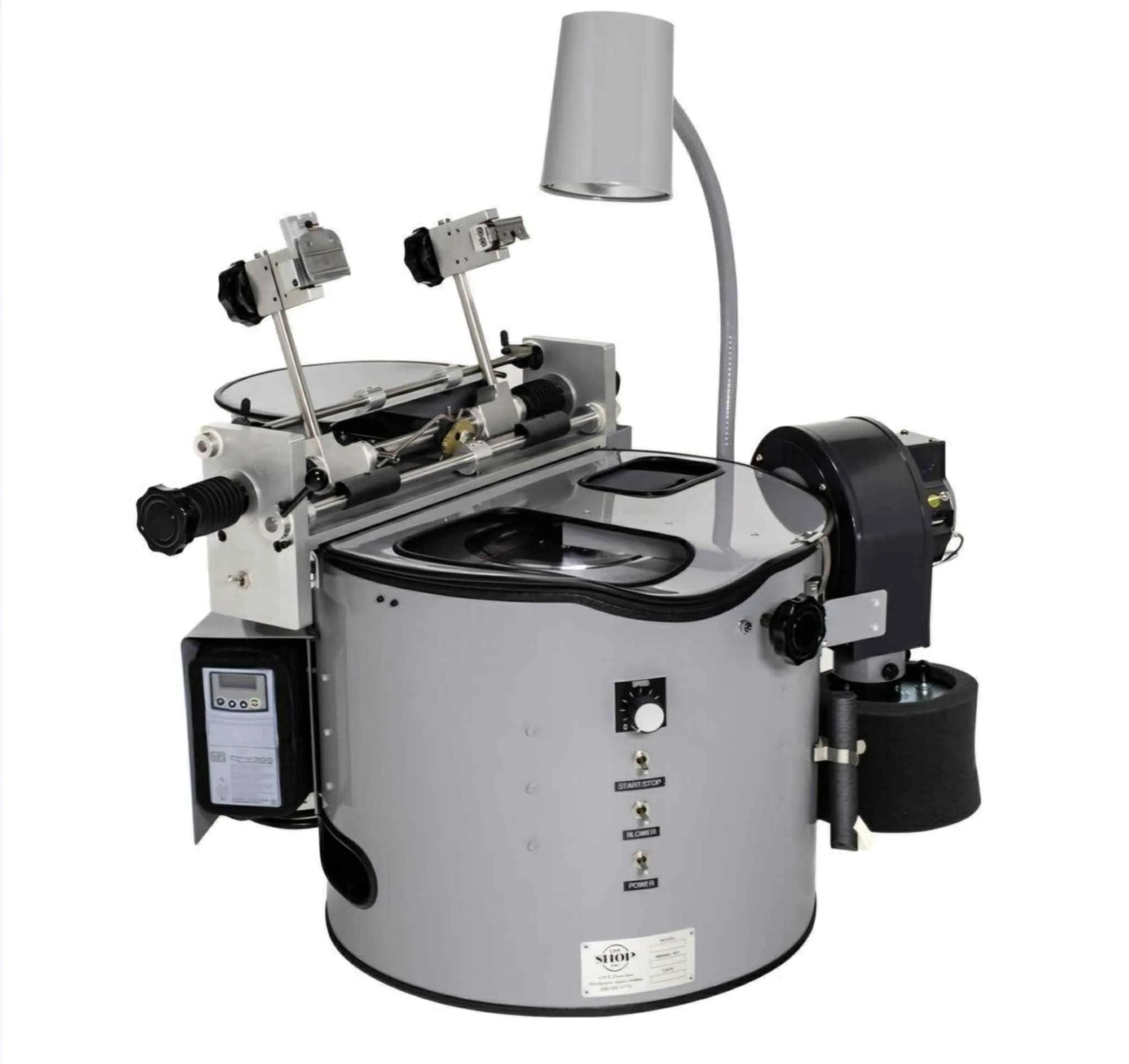 A machine used for precision scientific experiments, featuring a cylindrical base with controls, a transparent lid, adjustable arms, and a lamp.