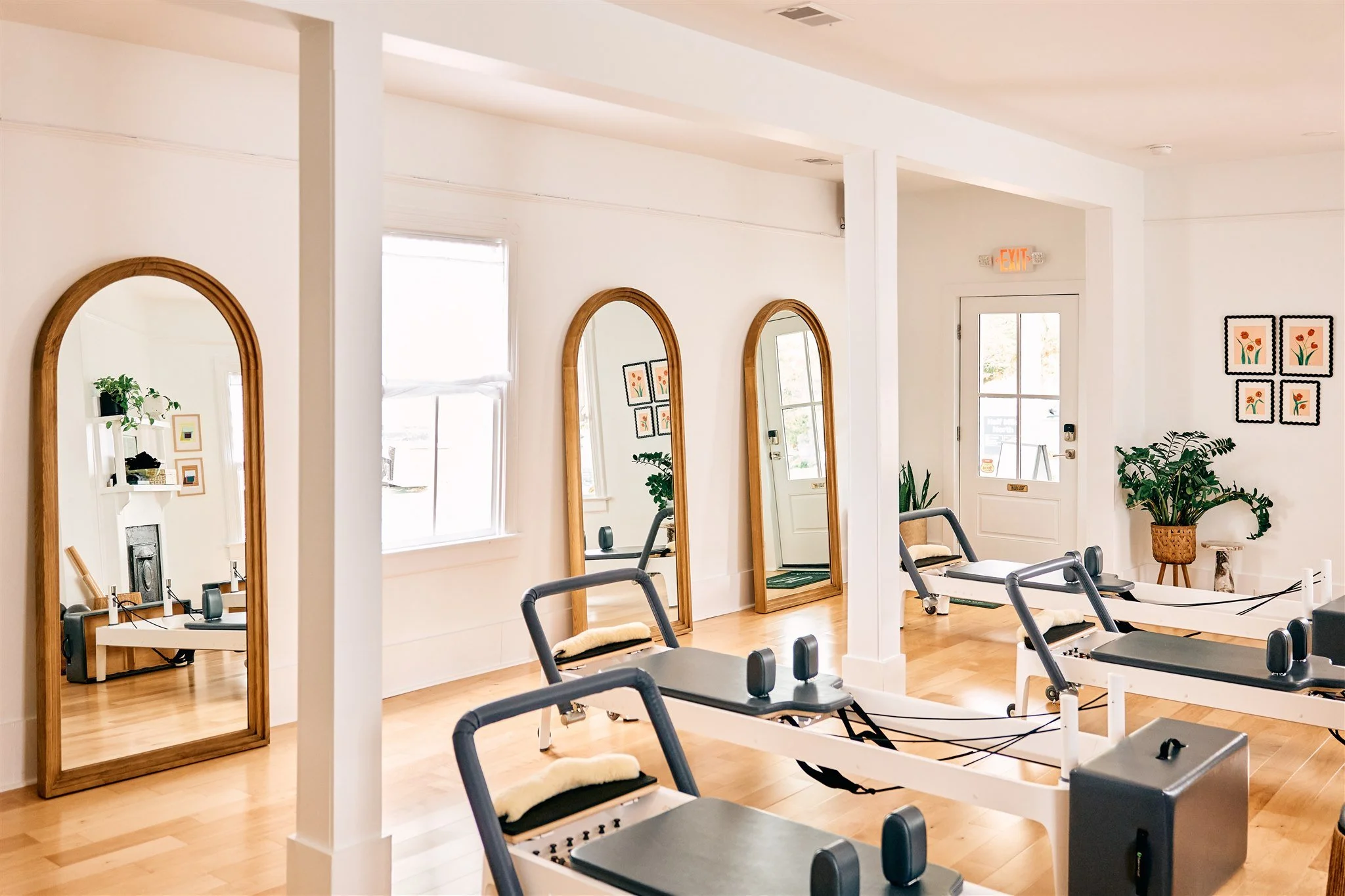 Wide open room with pillars with five reformers and arched mirrors.