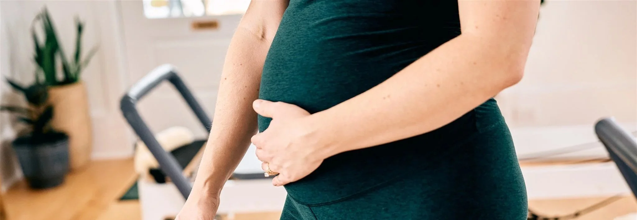 a hand wrapped around a pregnant belly in a dark green spandex outfit