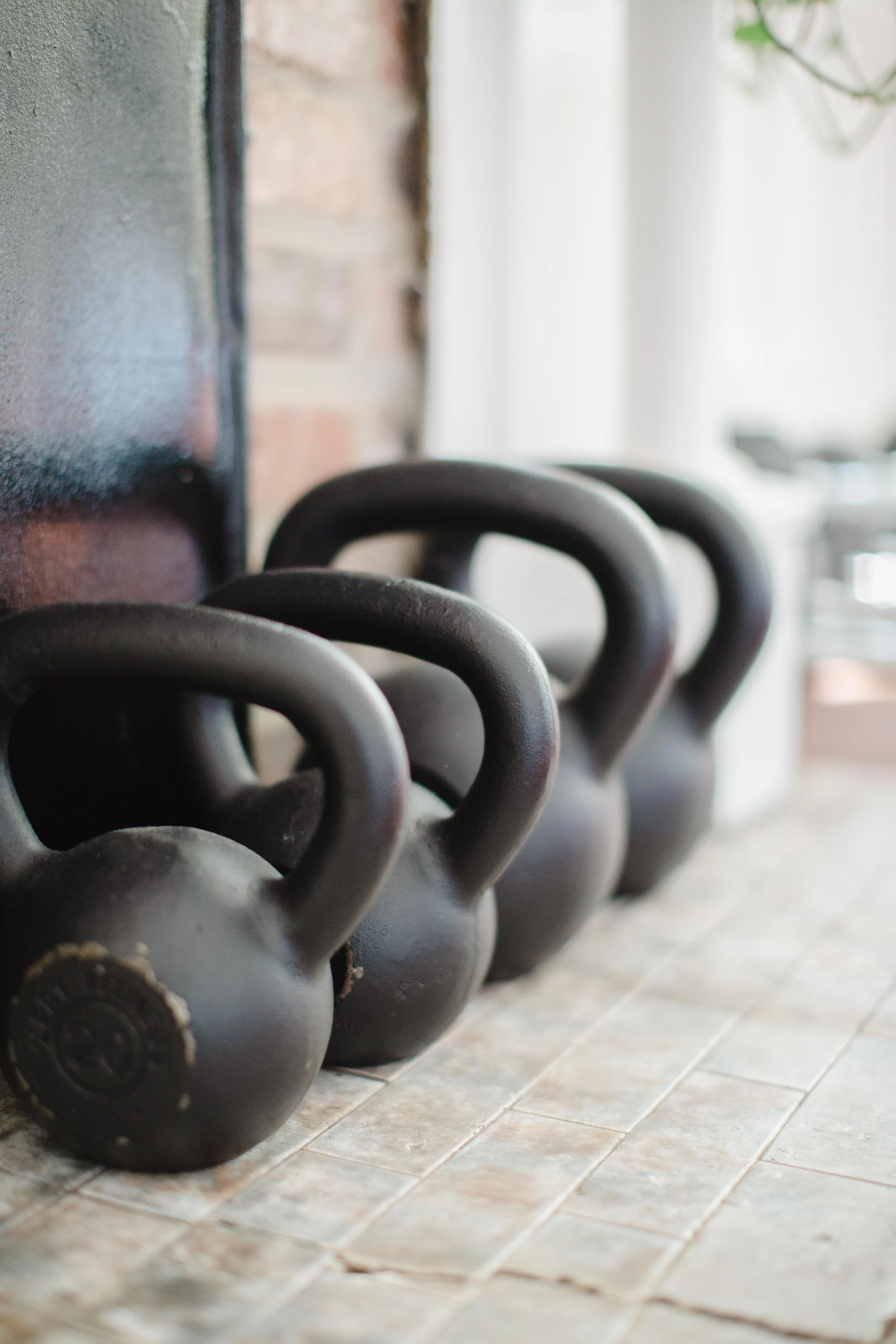 Various sized kettlebells against a brick wall