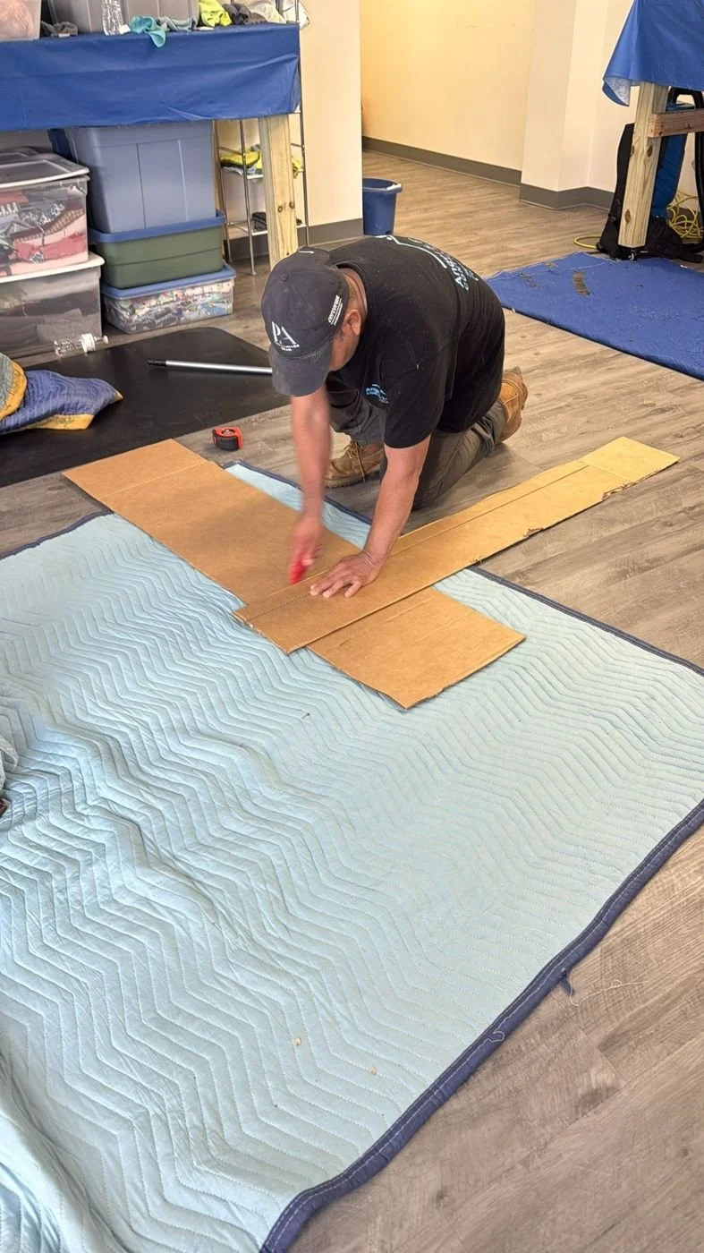 Crew member cutting cardboard to protect contents on a pack-out
