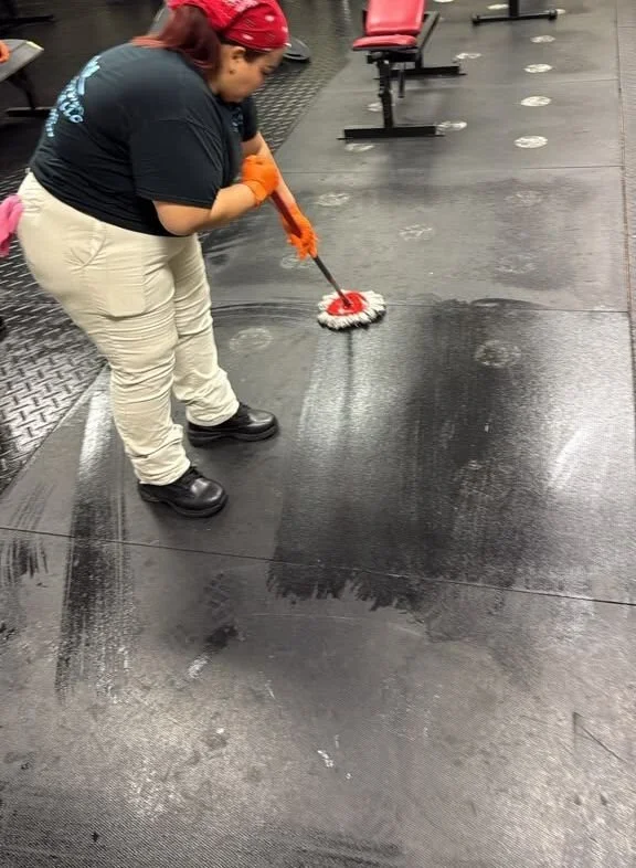 Crew member mopping a rubber gym floor