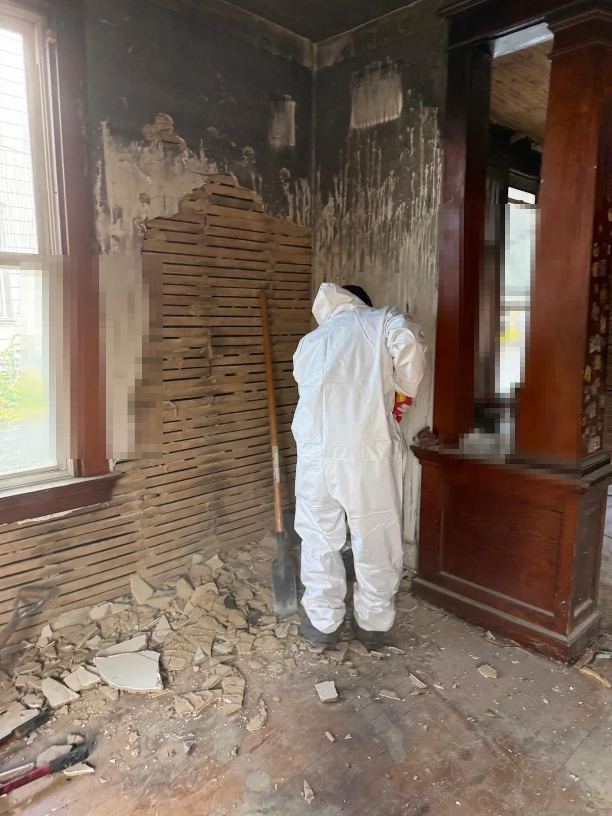 Crew member in protective suit demolishing a fire-damaged wall