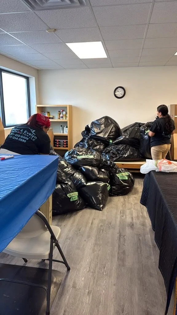 Crew in Angel & Evelyn Contractor shirts sorting bagged contents in a pack-out staging room