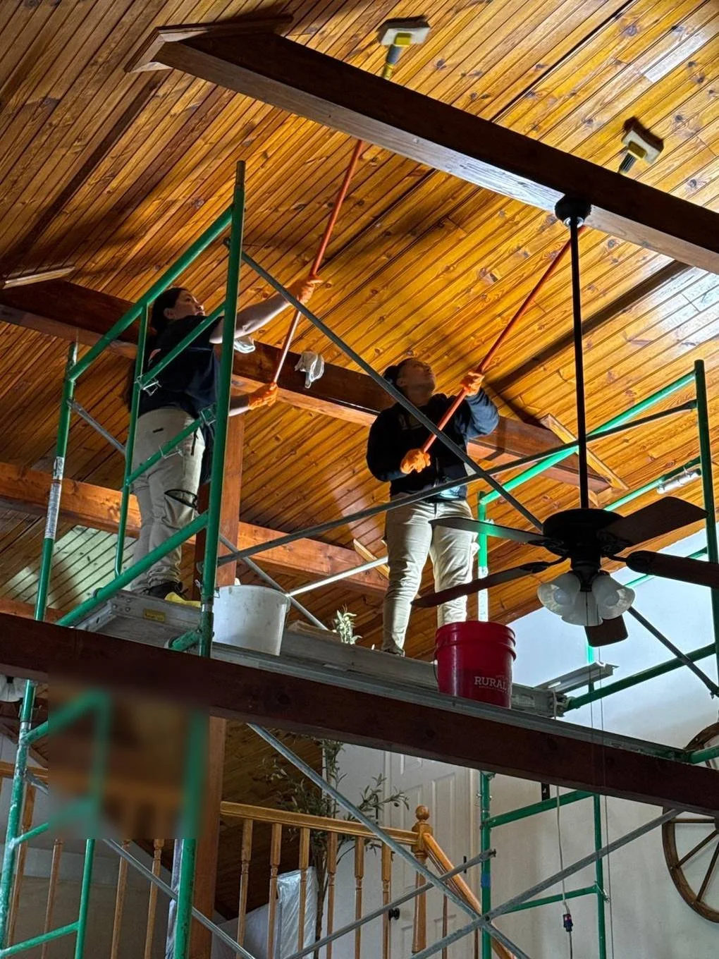 Crew members on scaffolding cleaning a wood plank ceiling