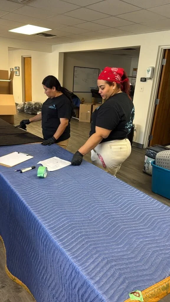 Two crew members in company shirts inventorying contents at a pack-out work table