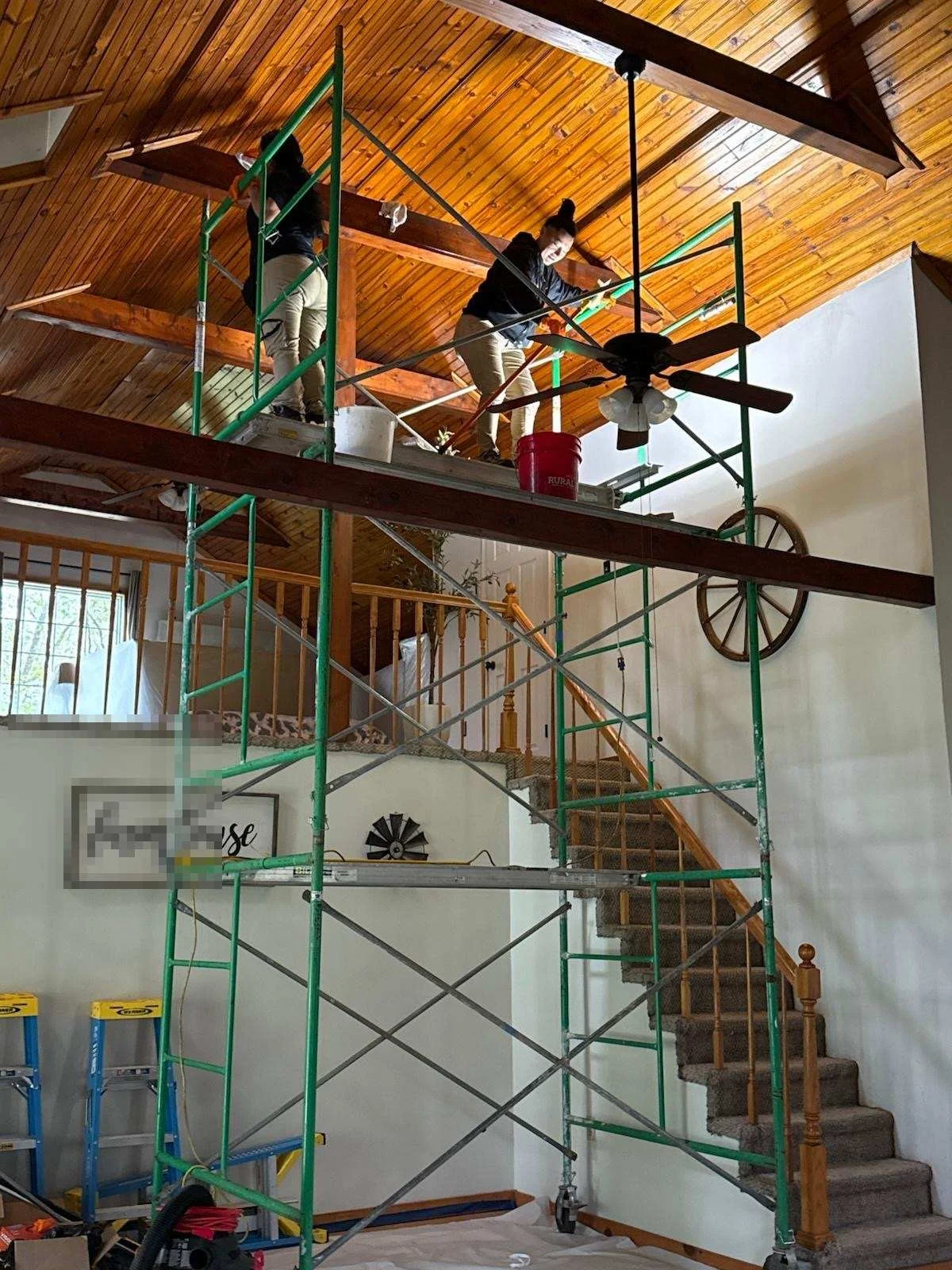Crew members on scaffolding cleaning a vaulted wood ceiling