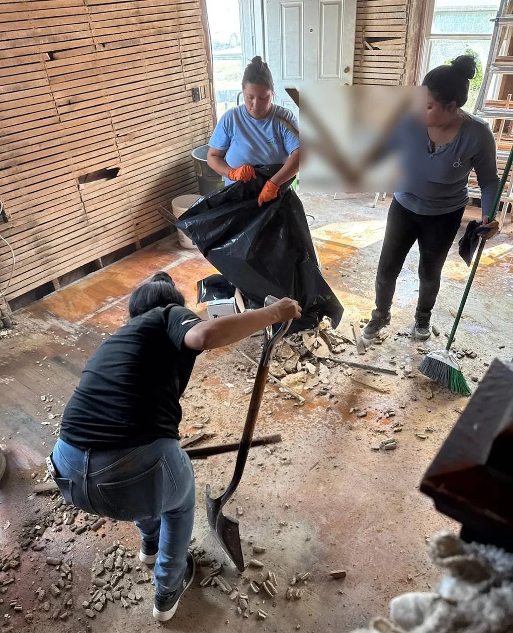 Crew members performing interior debris cleanup during home restoration