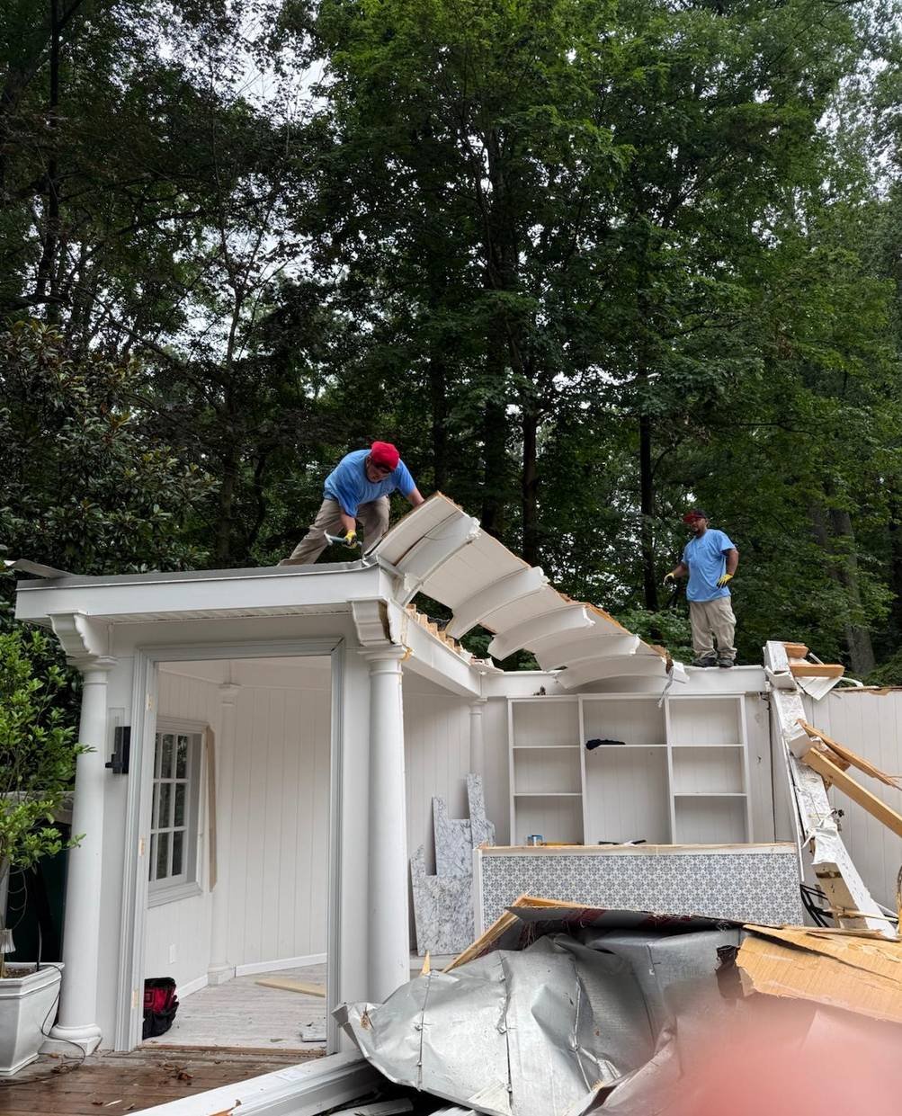 Two crew members performing outdoor roof demolition