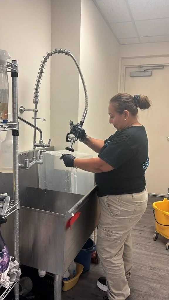 Crew member doing on-site contents cleaning of a storage bin at a utility sink
