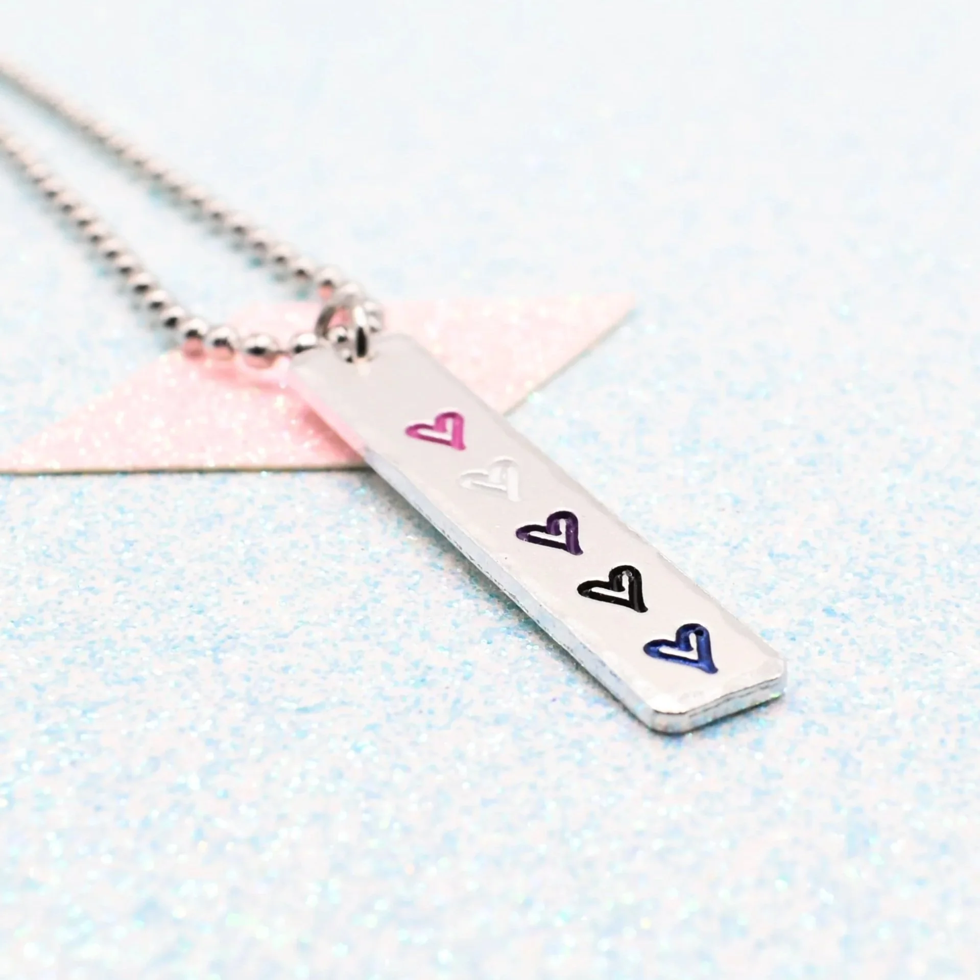 Vertical bar necklace featuring genderfluid flag enamel hearts pink white purple black blue