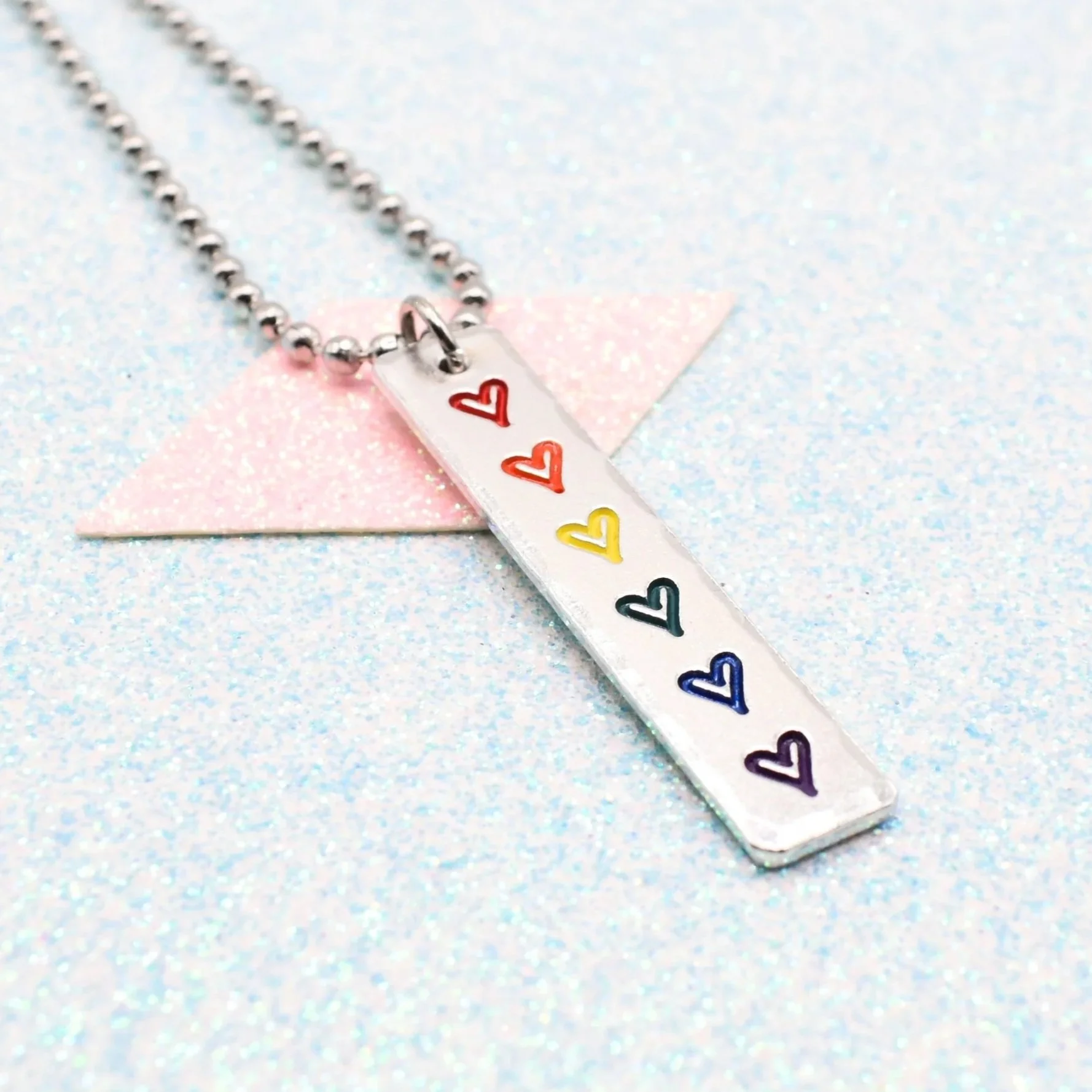 Vertical bar necklace featuring rainbow flag enamel hearts
