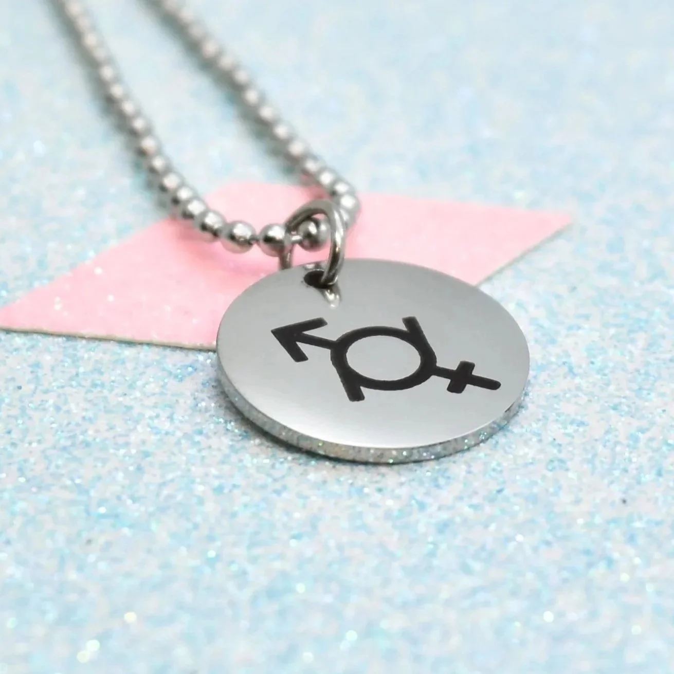 "Stainless steel genderfluid symbol necklace on glitter background"