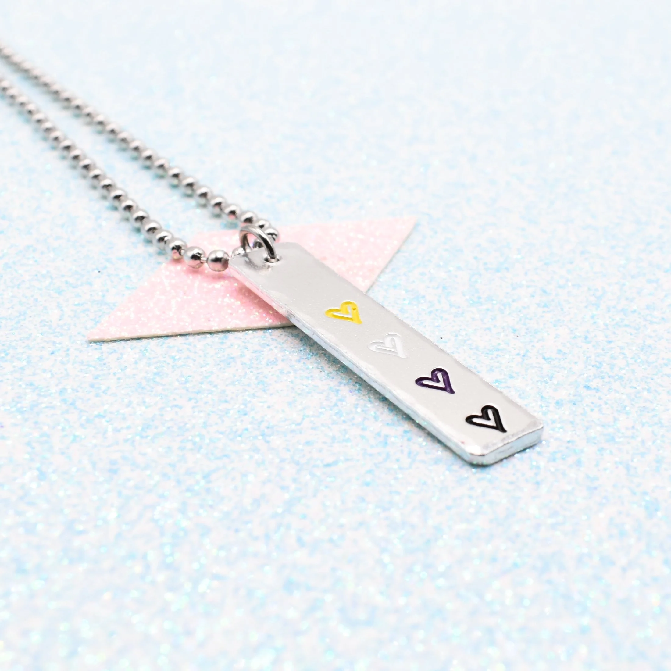 Vertical bar necklace featuring non-binary flag enamel hearts yellow white purple black