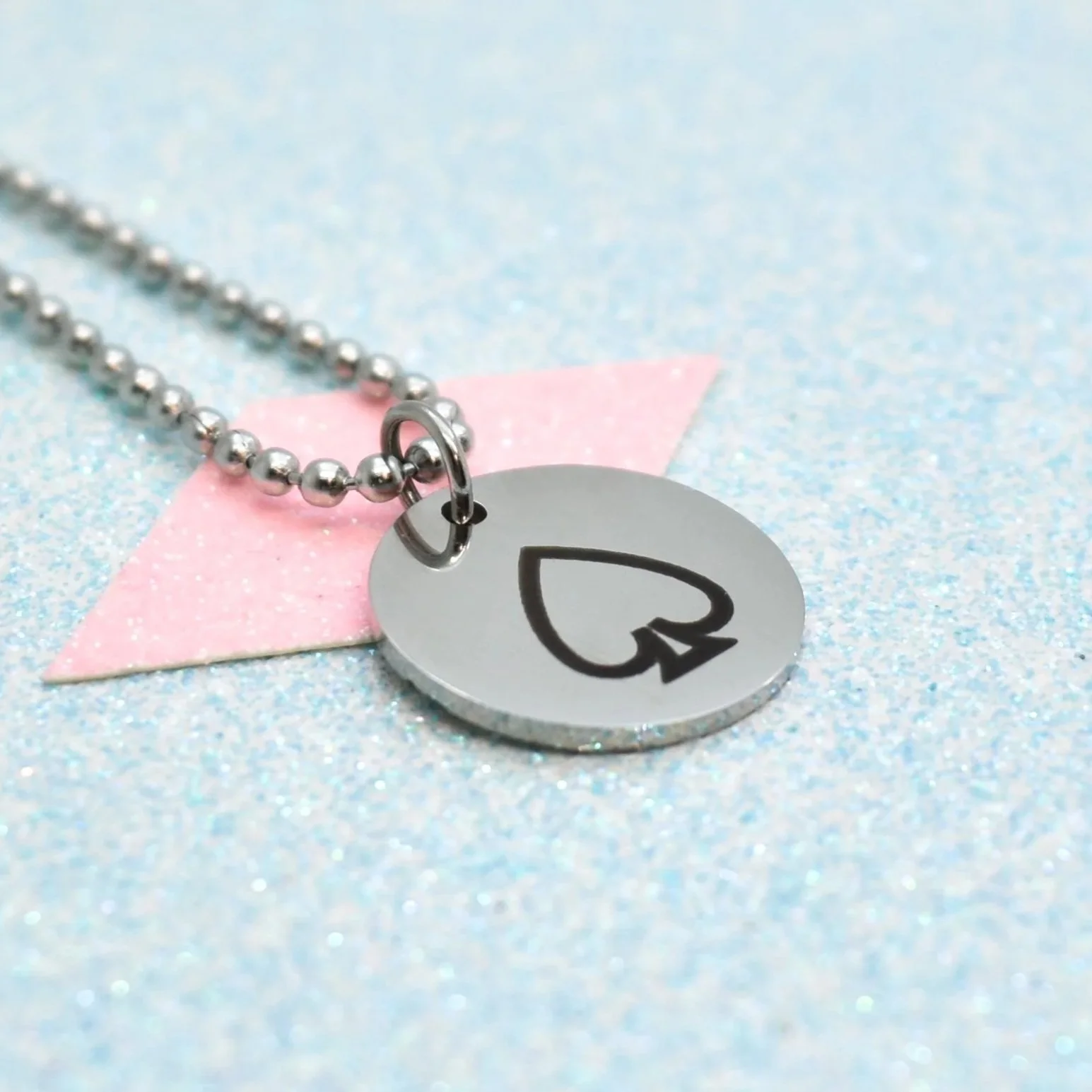 "Close-up of asexual pride necklace on glitter background"