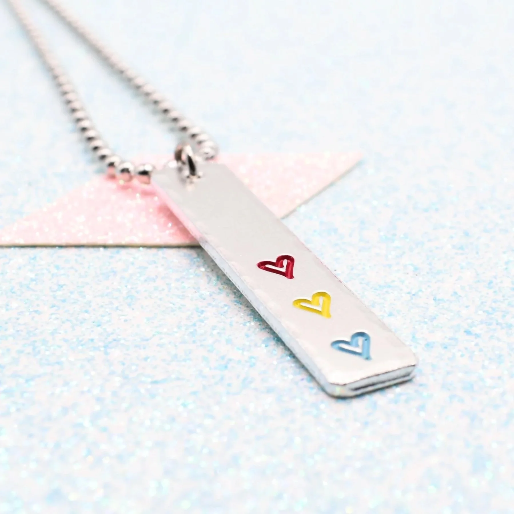 Vertical bar necklace featuring pansexual flag enamel hearts pink yellow blue