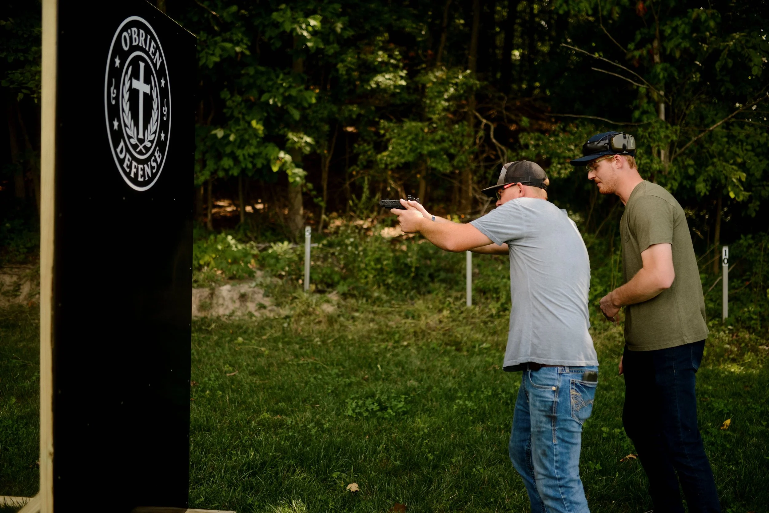 Firearms instructor with student shooting around barricade