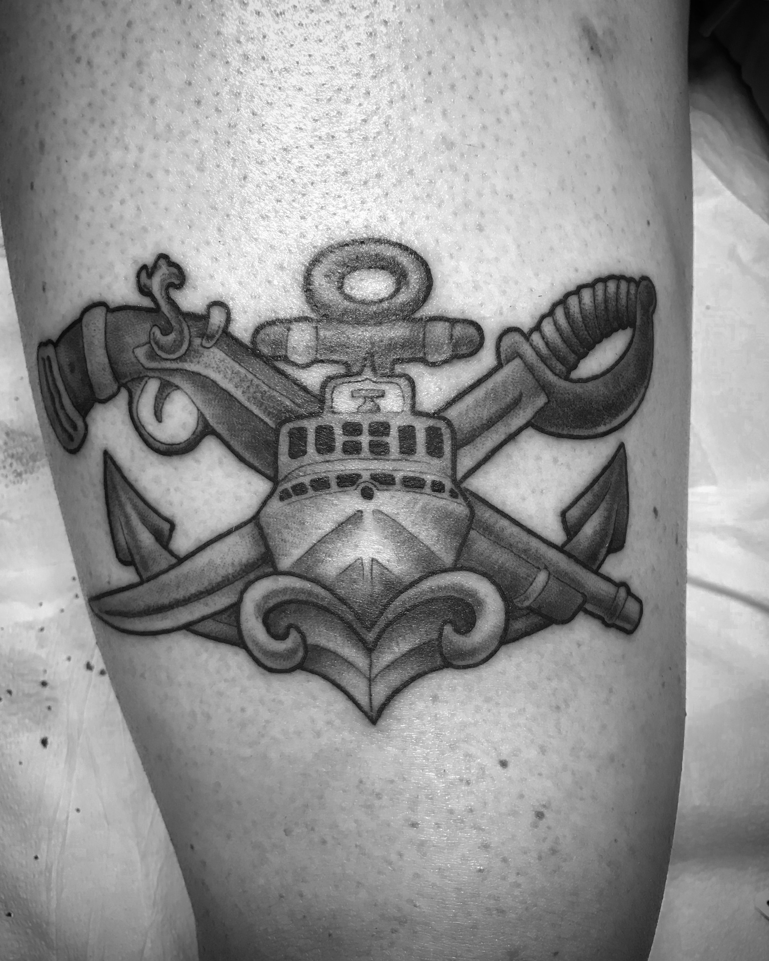 Tattoo of the U.S. Navy Special warfare combat crewman senior warfare pin. A MK V boat with a crossed flintlock pistol and cutlass with an  anchor underneath, surrounded by decorative flourishes.
