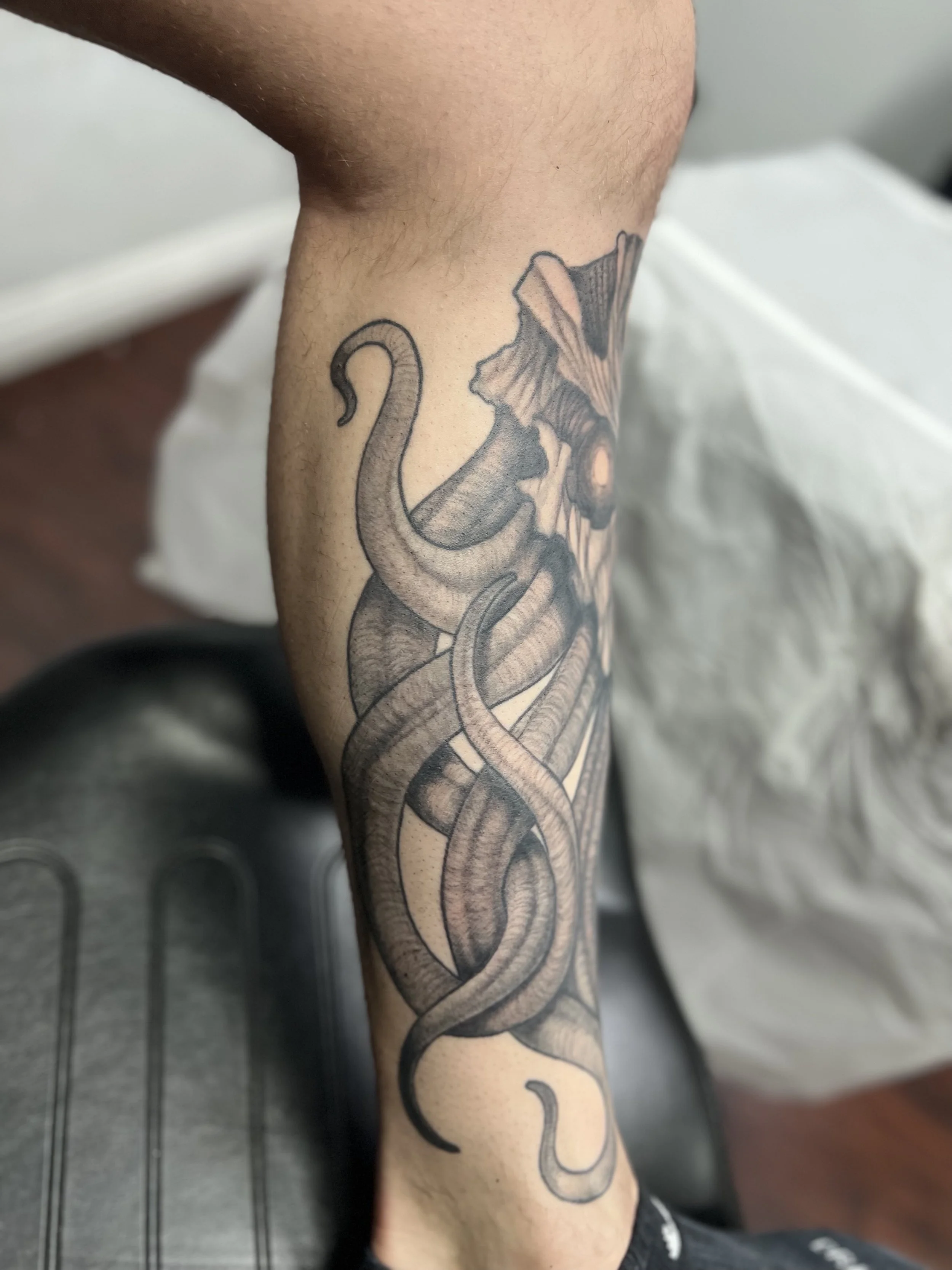 Tattoo of several intertwined octopus tentacles on a person's forearm.