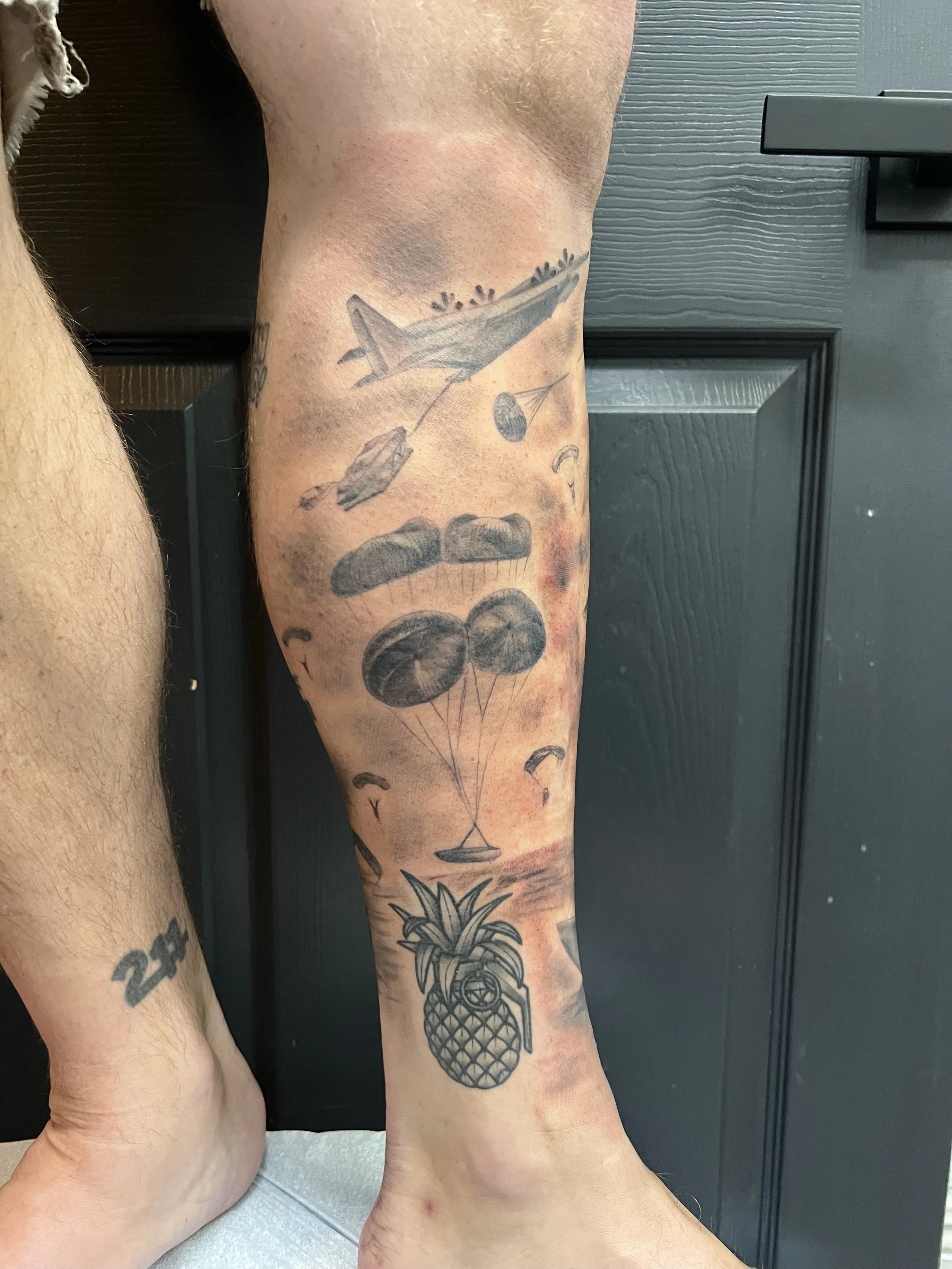 Tattoo of a drone flying in the sky with clouds and parasails, and a pineapple with a clock on it at the bottom of the leg.