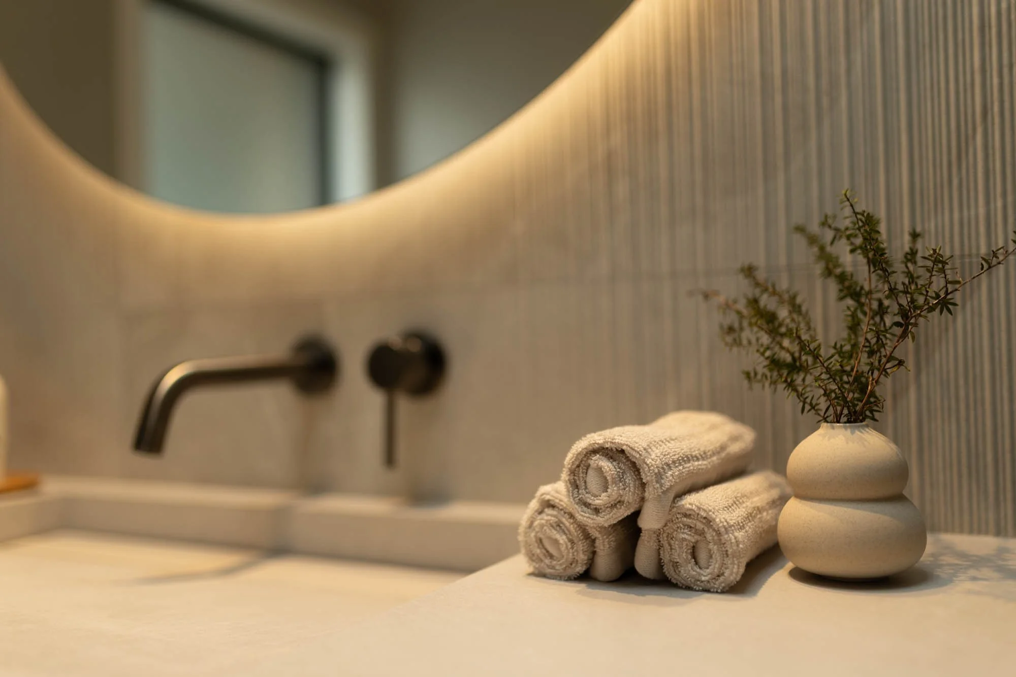 Close-up of the designer vanity with a large backlit mirror and luxurious spa-like details in the main bathroom at Ocean View Te Arai.