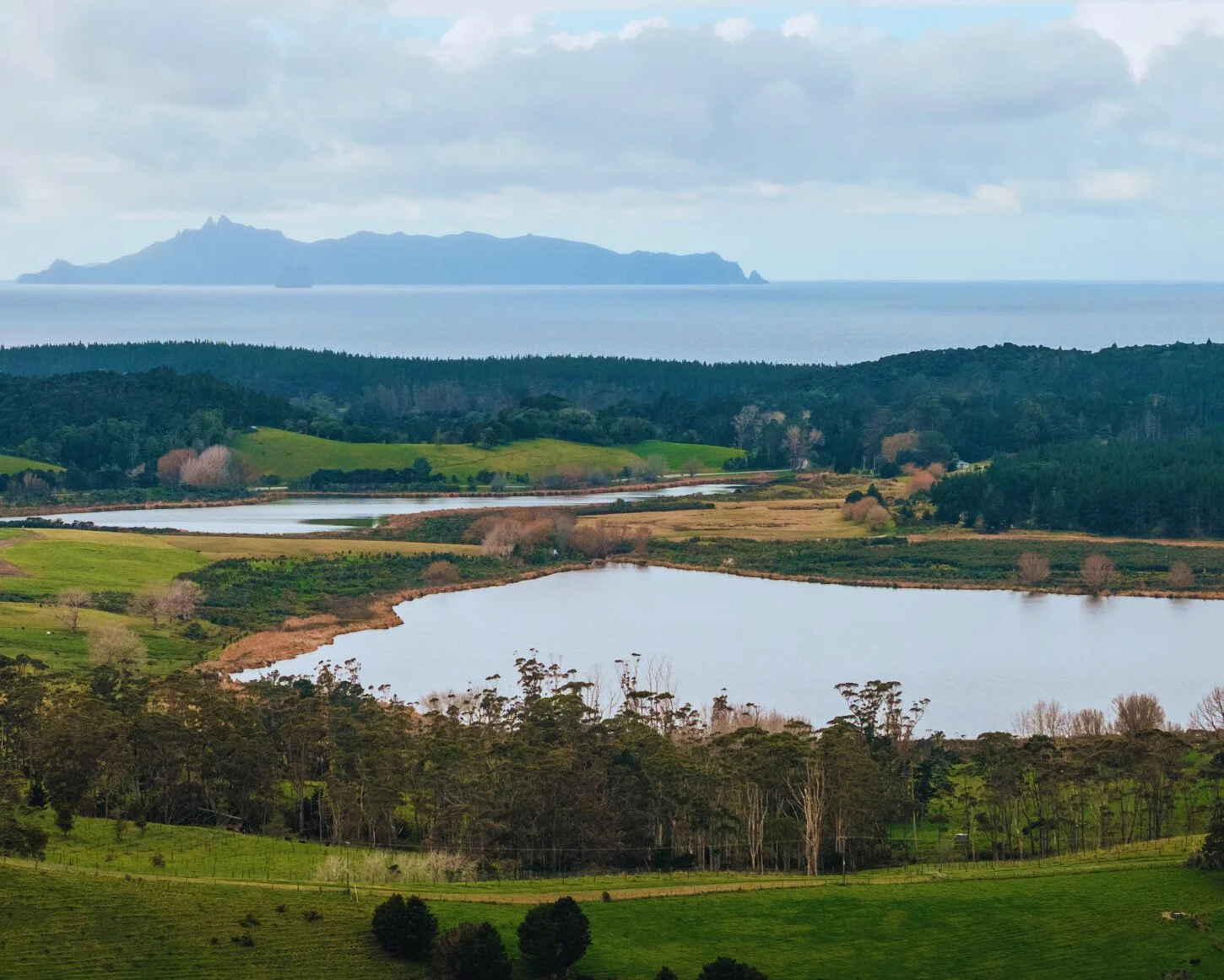 The stunning ocean, lake and farmland view, taken from the front deck of Ocean View Te Arai.