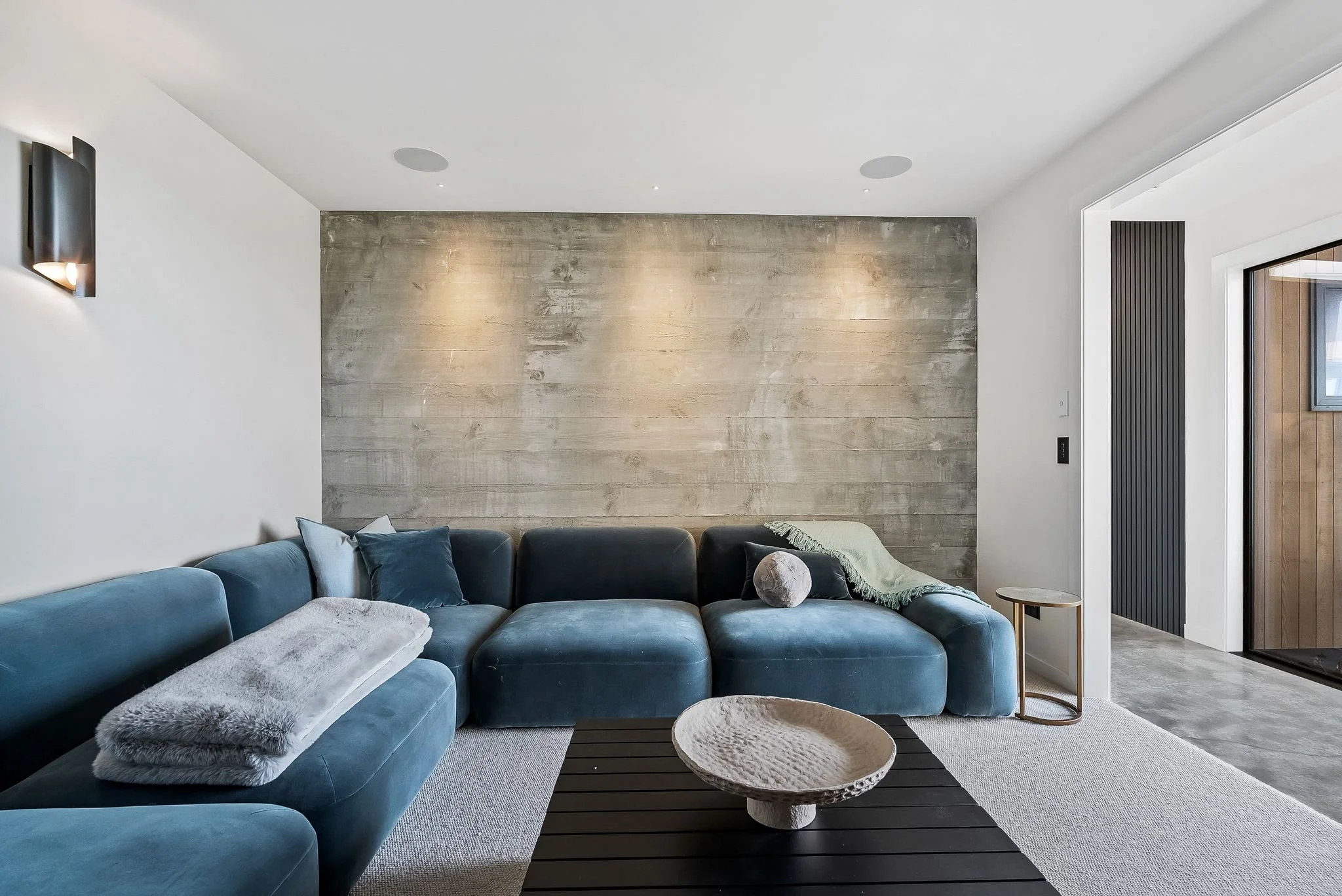 Luxurious media room at Ocean View Te Arai featuring sumptuous designer couches, a 75-inch TV with surround sound, and ambient theatre lighting with views to the expansive ocean view.