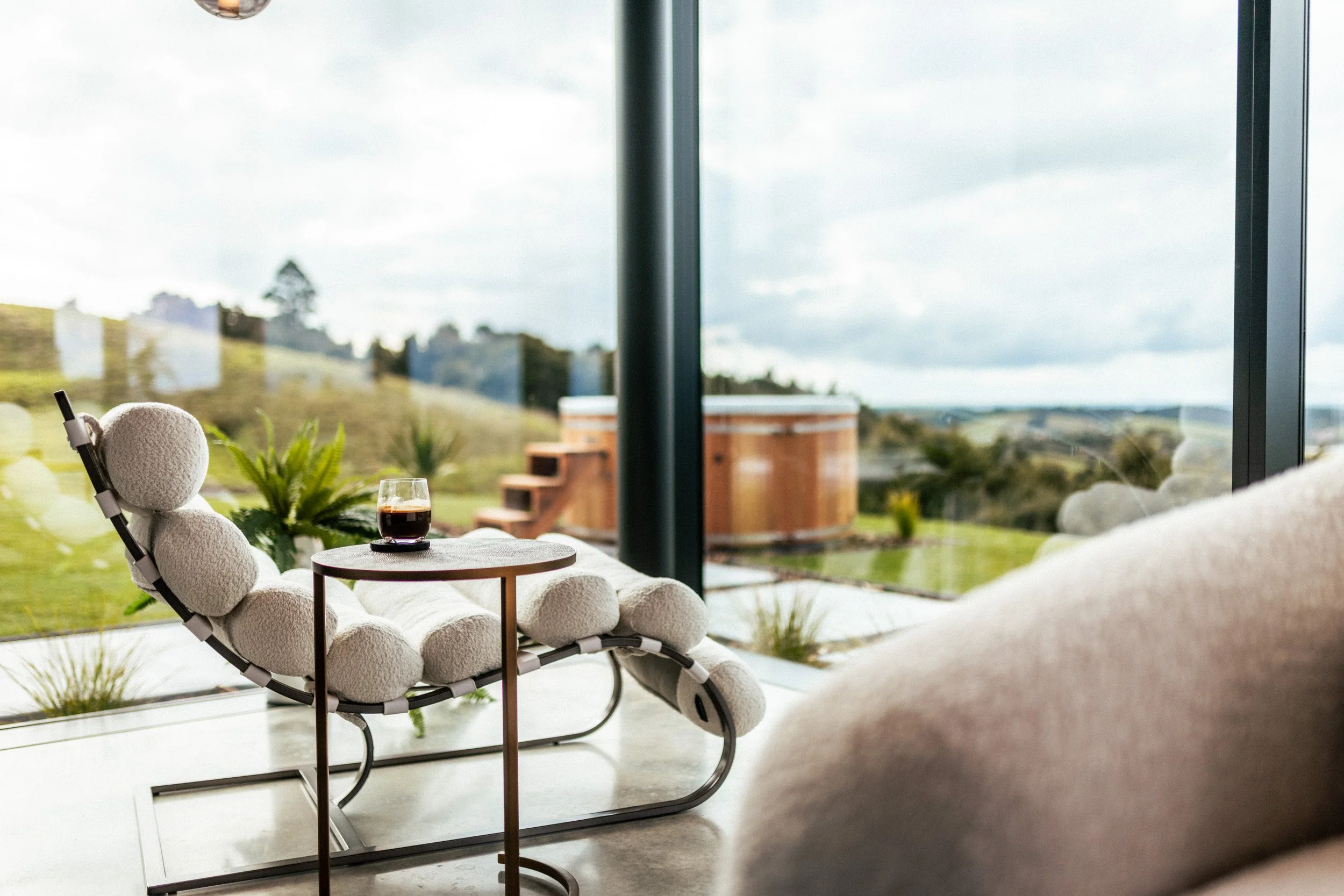 Chaise lounge in the lounge area at Ocean View Te Arai, with floor-to-ceiling glass maximising breathtaking views of the Pacific Ocean, Hen and Chickens Islands and the pine forests of Te Arai Links.