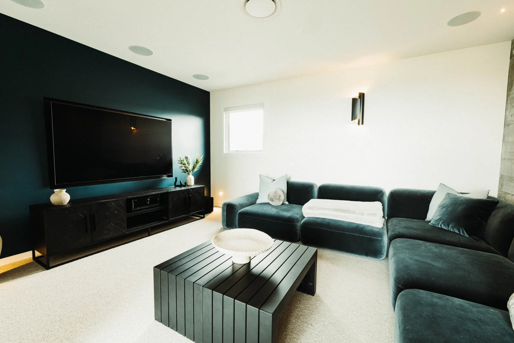 Luxurious media room at Ocean View Te Arai featuring sumptuous designer couches, a 75-inch TV with surround sound, and ambient theatre lighting for a premium home cinema experience.