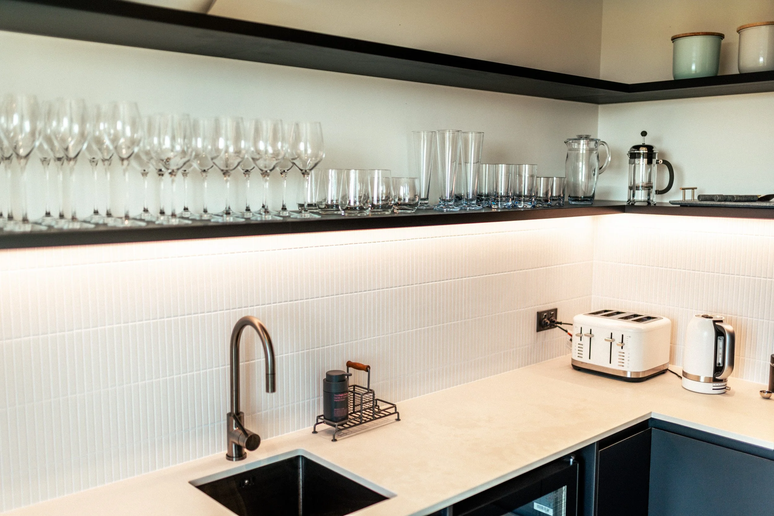 Fully equipped scullery at Ocean View Te Arai, featuring a wine fridge, state-of-the-art coffee machine, Kitchen Aid appliances with views through the full-length window across the coastal landscape.