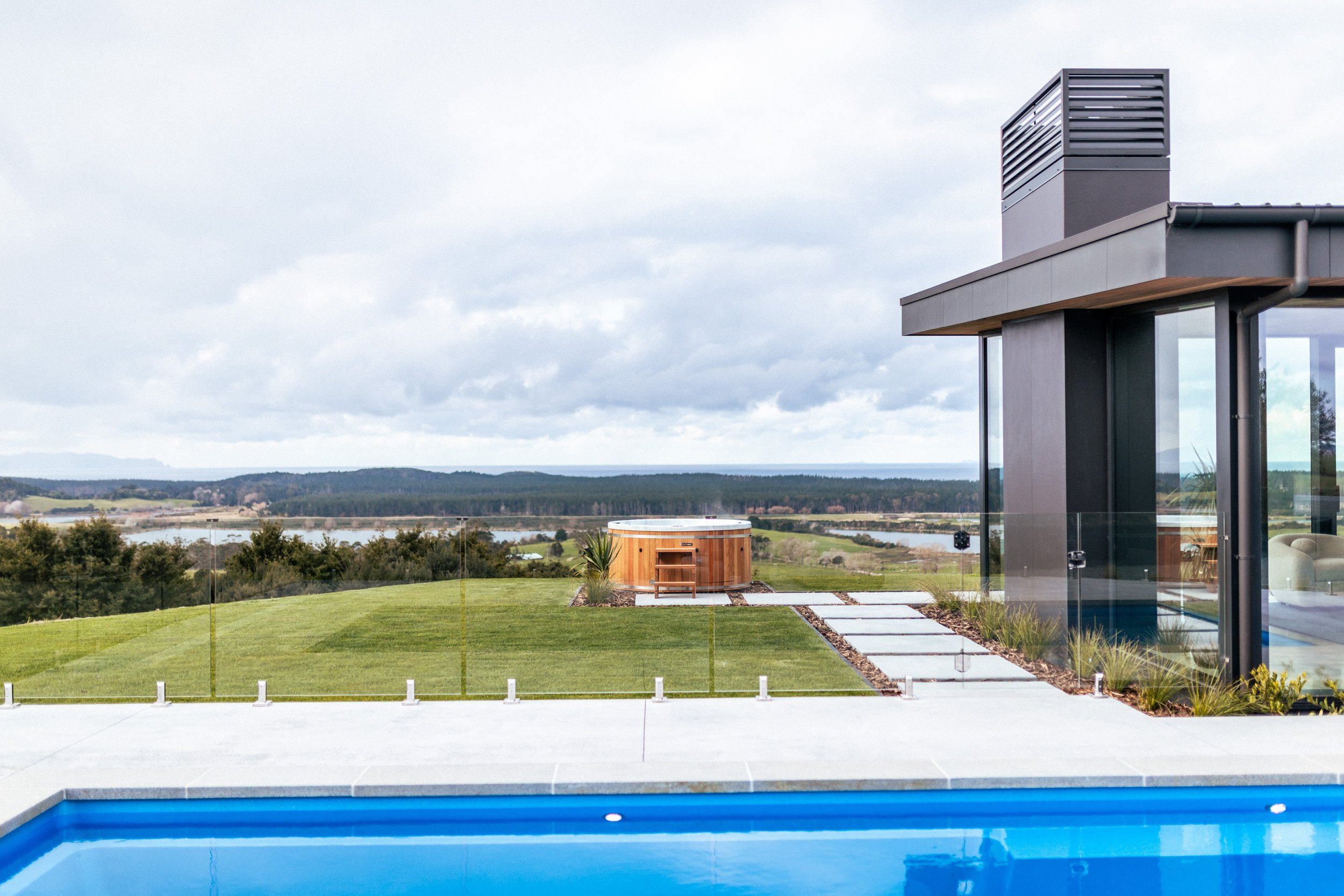 Illuminated pool and spa at Ocean View Te Arai, with uninterrupted views of the ocean, lake, pine forests and rolling farmland.