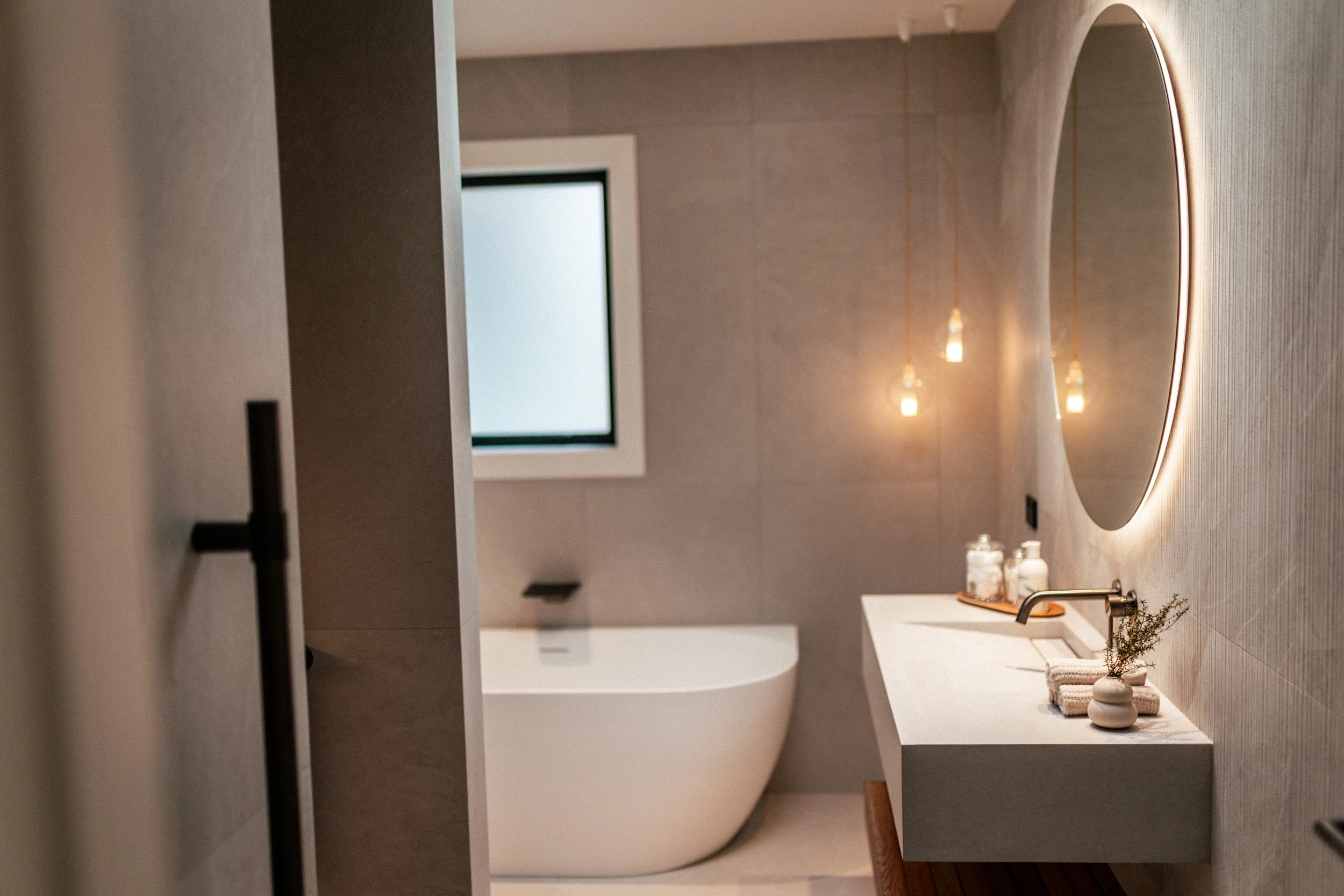 Main bathroom at Ocean View Te Arai featuring a walk-in shower, freestanding bath, floor-to-ceiling tiles, bespoke vanity, designer lighting, and underfloor heating for a luxurious spa-like experience.