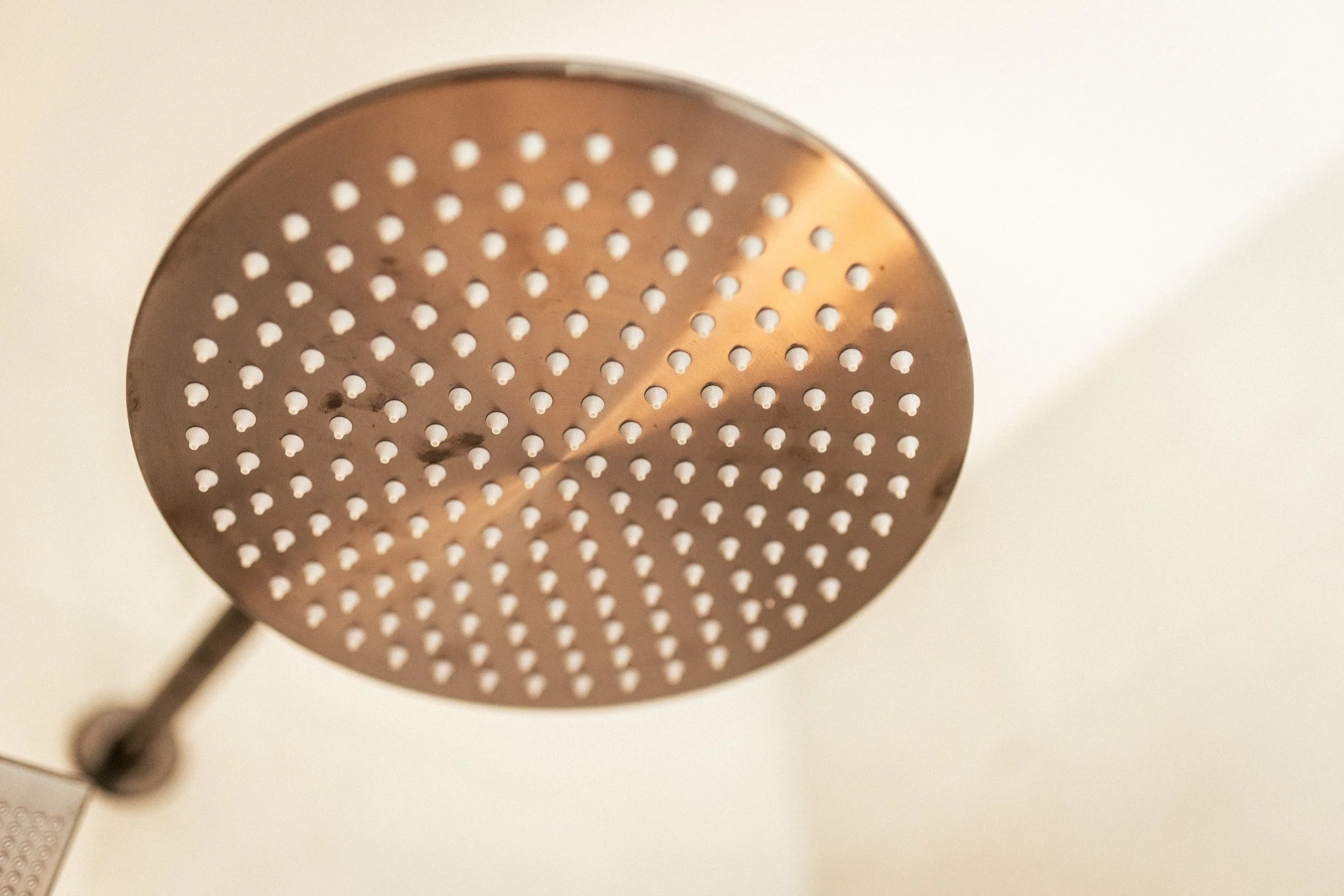 Waterfall shower head in walk-in shower with feature niche lighting and luxurious spa-like details in the main bathroom at Ocean View Te Arai.
