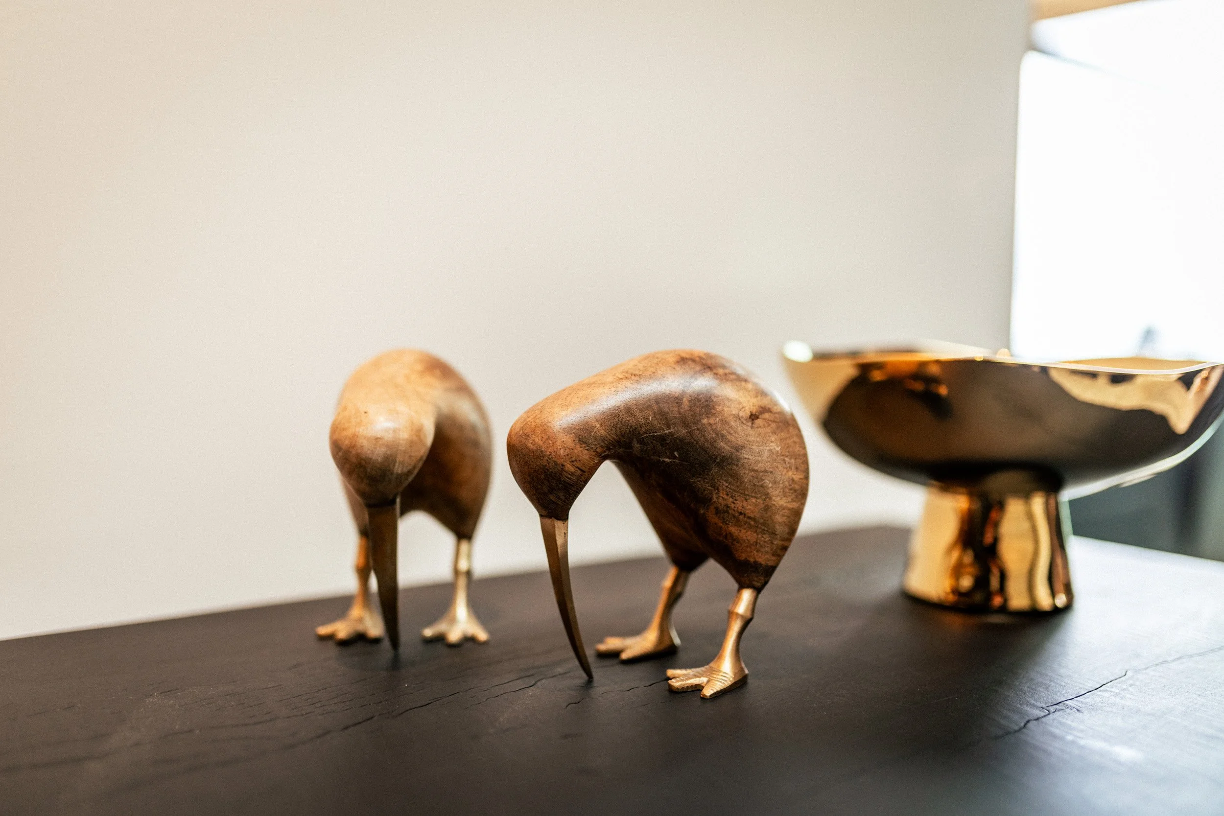 Close-up of two wooden designer kiwi ornaments and a gold bowl on the entrance console table at Ocean View Te Arai, adding a refined New Zealand touch to the luxury coastal interior.
