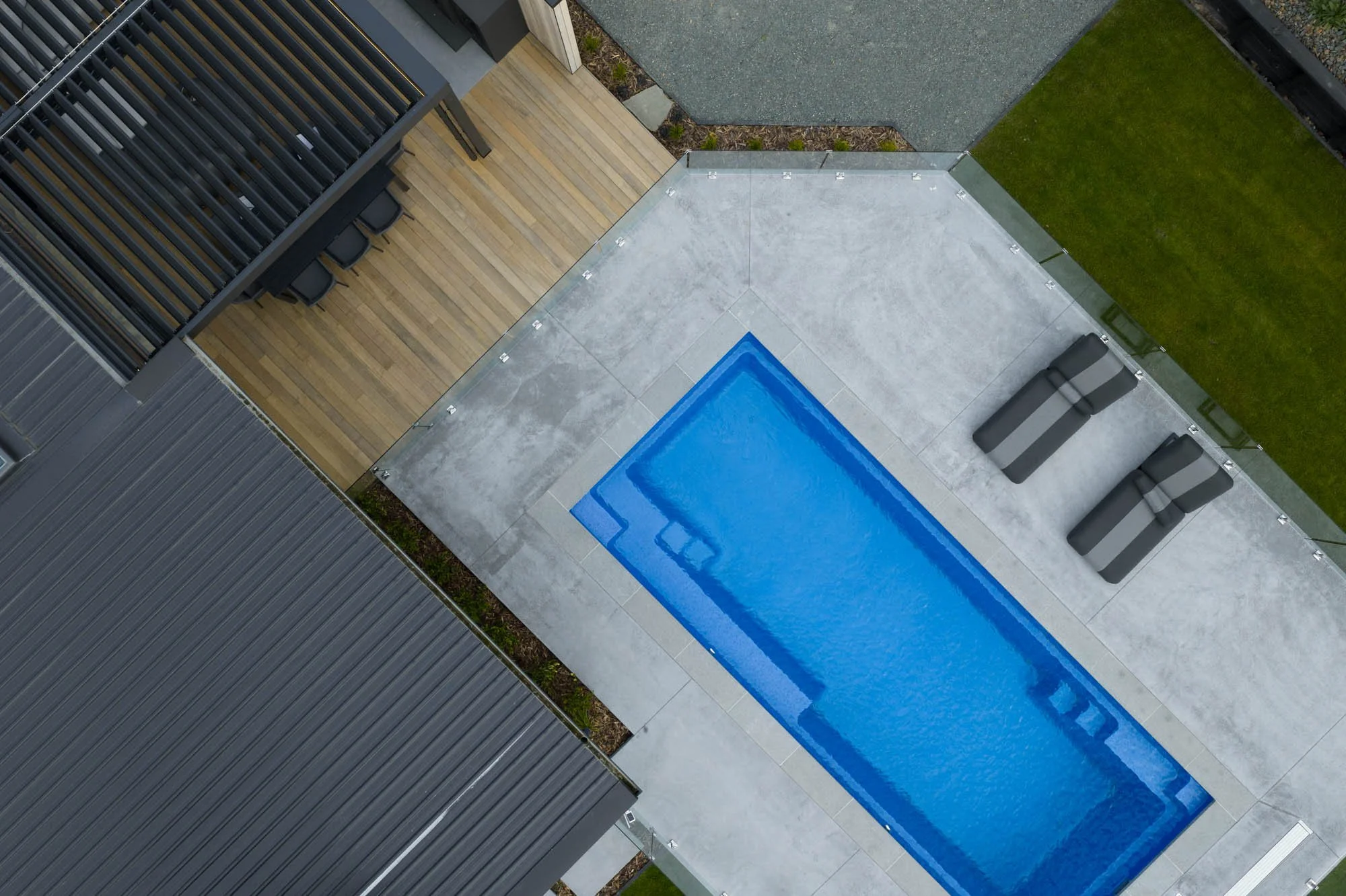 Overhead shot of the swimming pool area at Ocean View Te Arai, with sun-drenched decks, sun loungers and louvre-covered outdoor entertaining area.