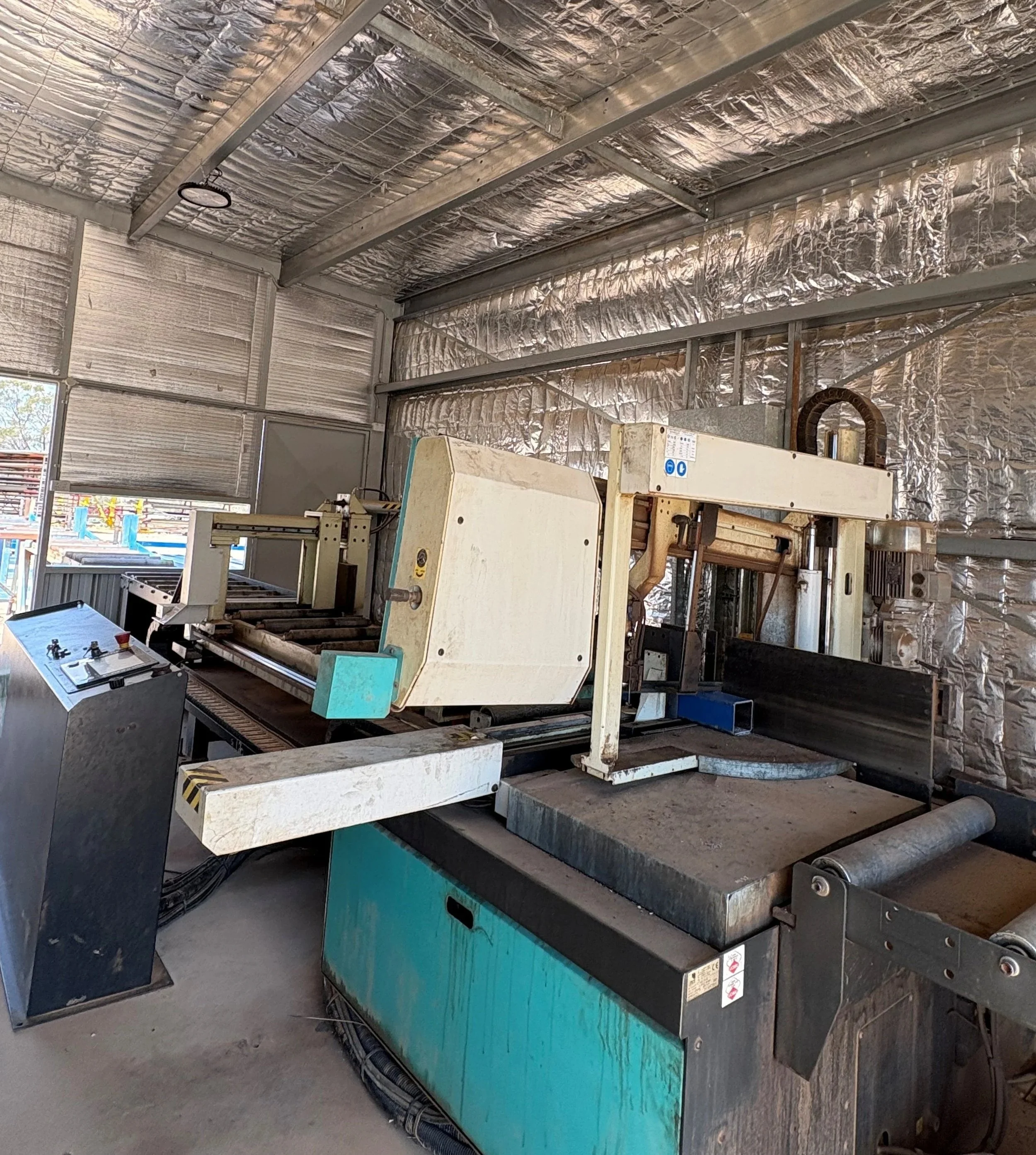Industrial workshop with machinery and equipment, metallic walls, and ventilation ducts.