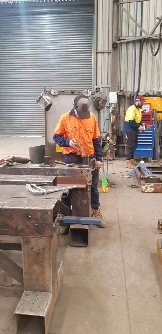 Work experience student is working on a steel beam inside the workshop.