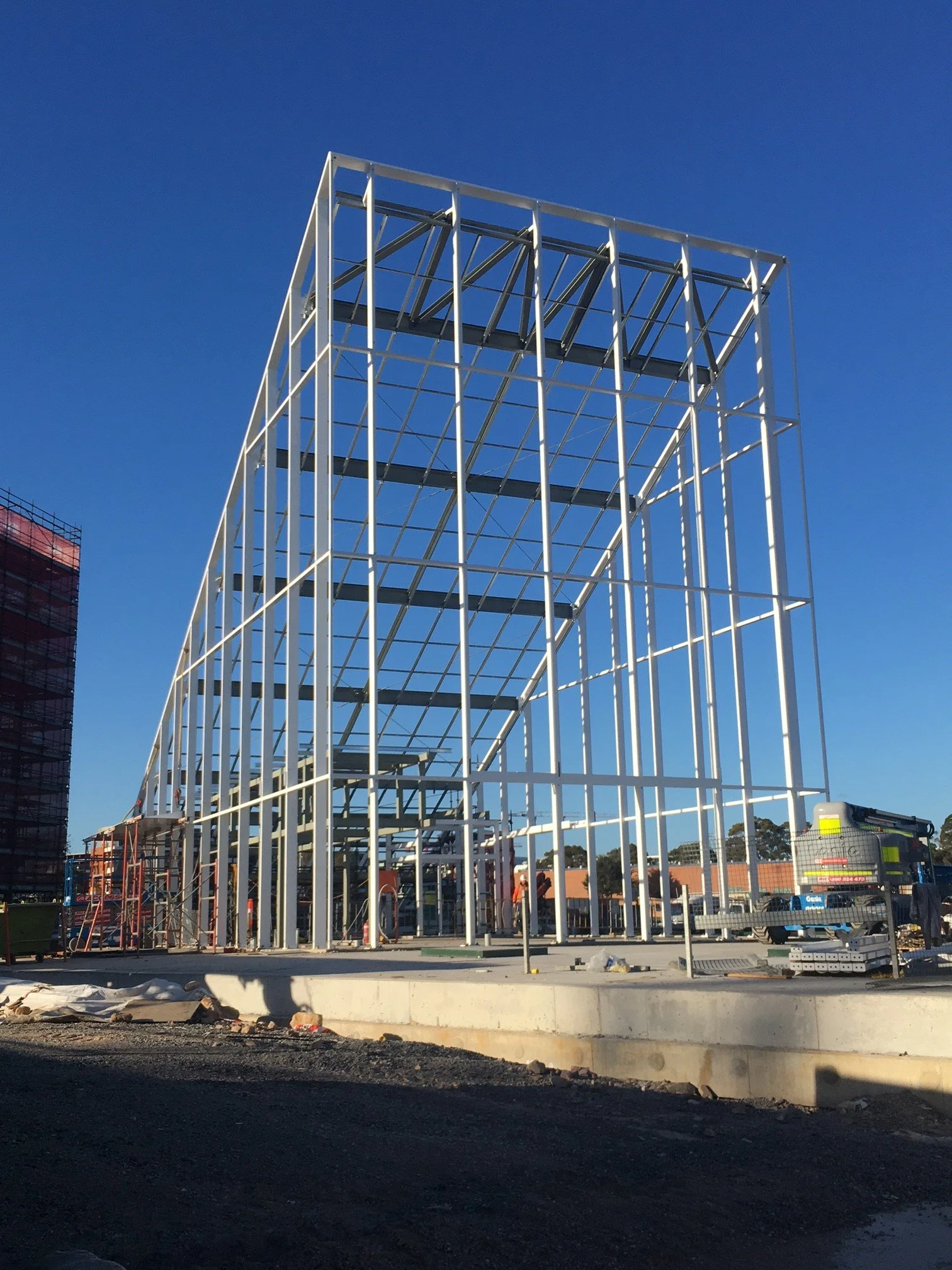 Steel framework of a building under construction against a blue sky.