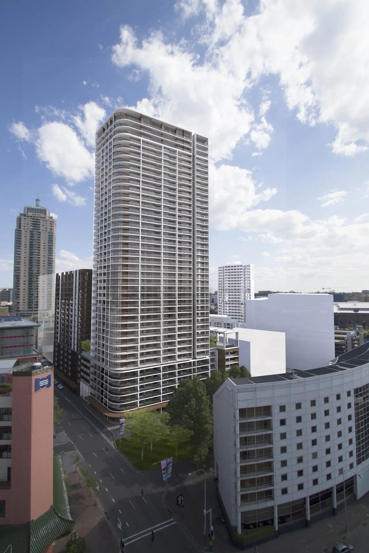 Cityscape with tall modern buildings under a partly cloudy sky, including a high-rise with rounded balconies and surrounding structures, with a street and greenery in the foreground.